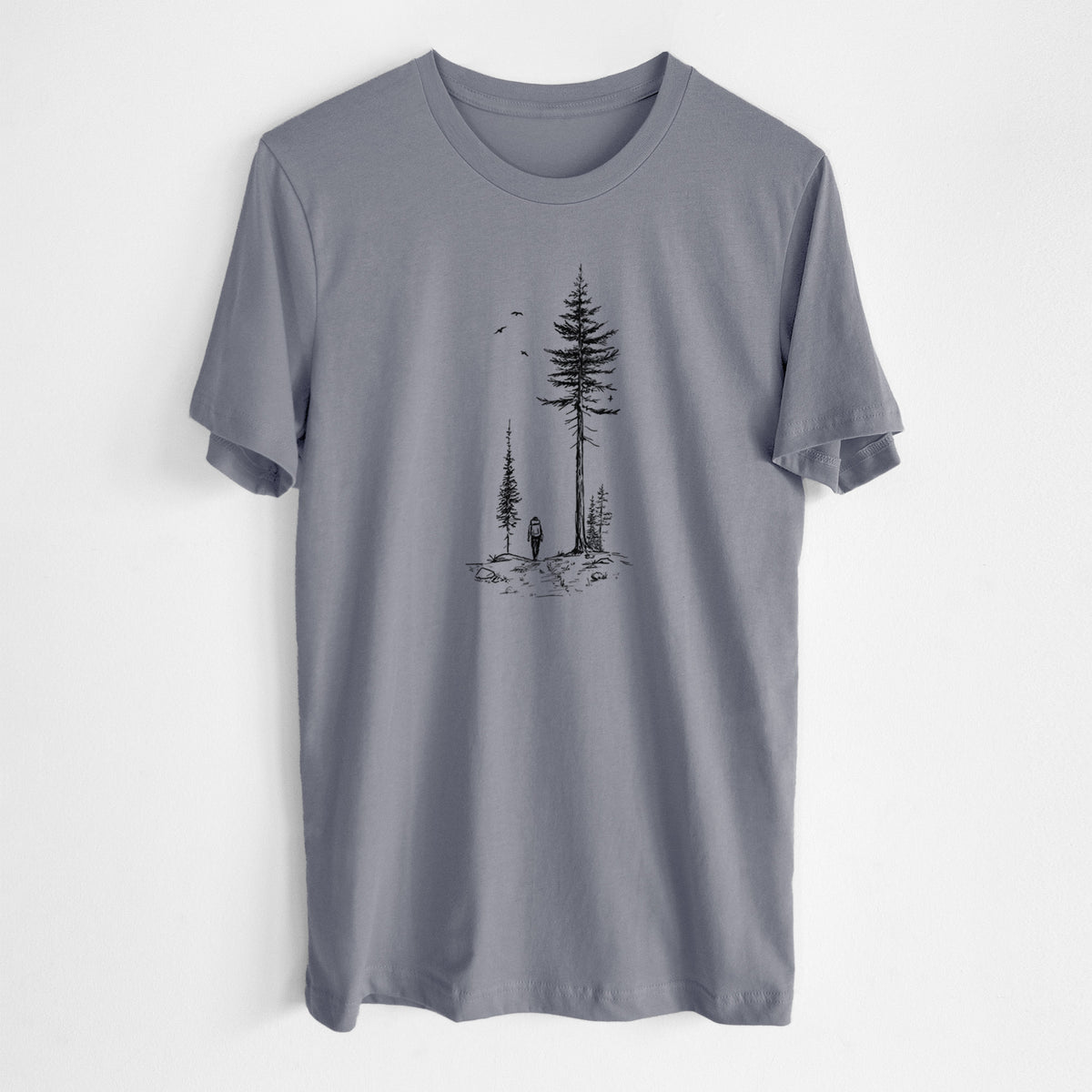 Storm grey lightweight cotton t-shirt laid flat, printed with a black ink illustration of a lone hiker walking between tall pine trees with birds overhead.
