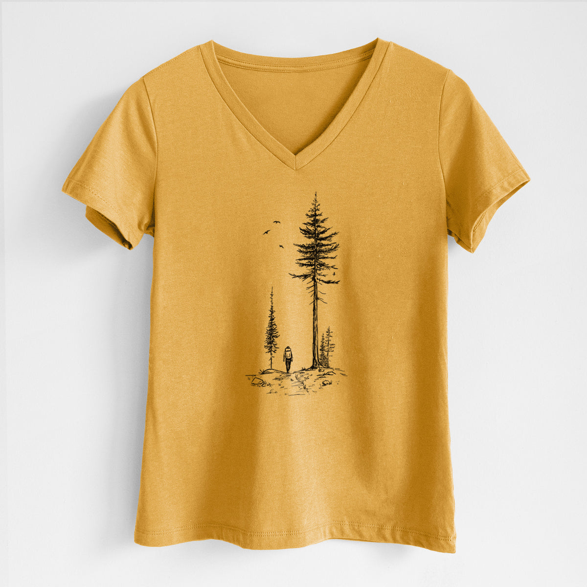 Honeycomb yellow women's relaxed fit cotton V-neck t-shirt laid flat, printed with a black ink illustration of a lone hiker walking between tall pine trees with birds overhead.