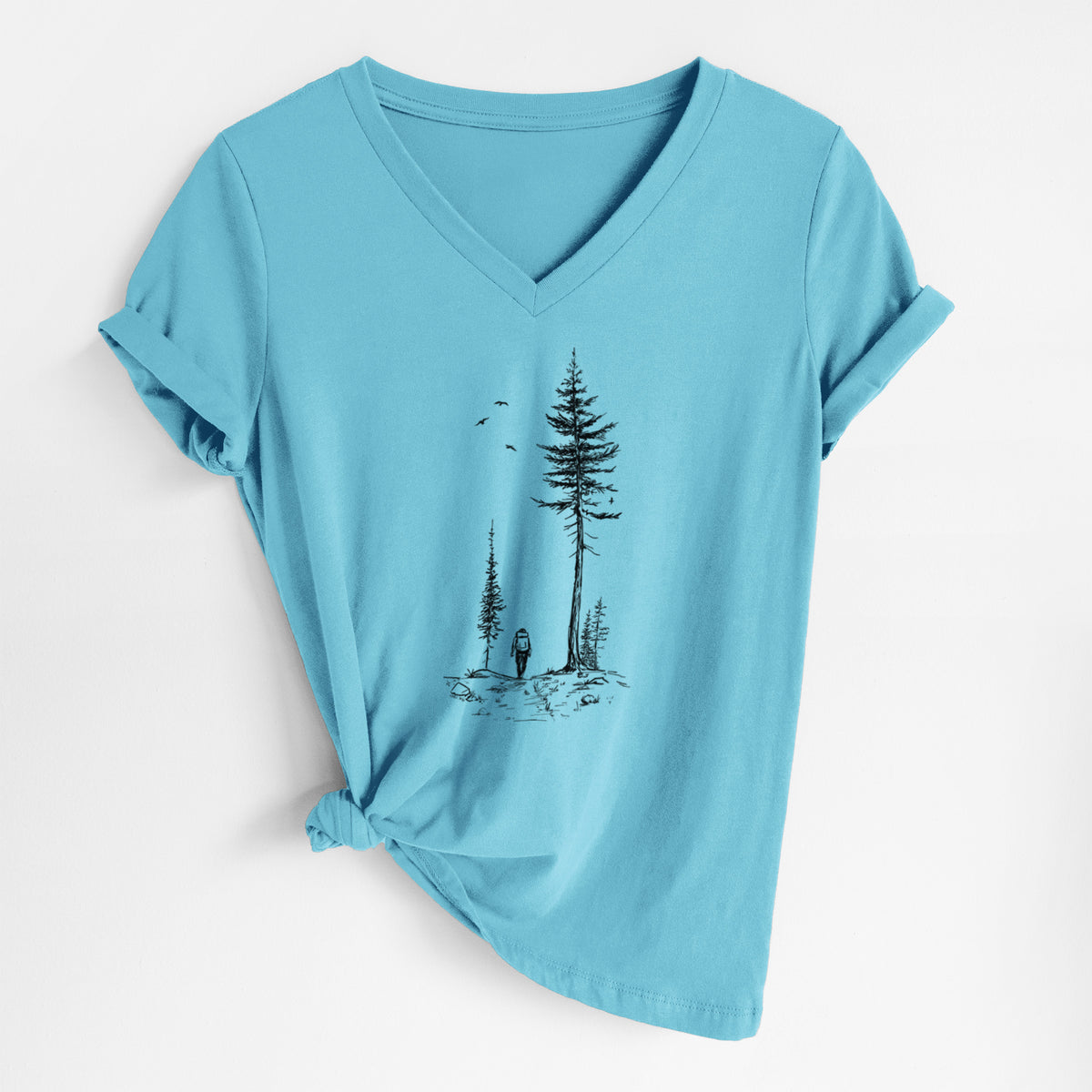 Turquoise women's relaxed fit cotton V-neck t-shirt laid flat, printed with a black ink illustration of a lone hiker walking between tall pine trees with birds overhead.