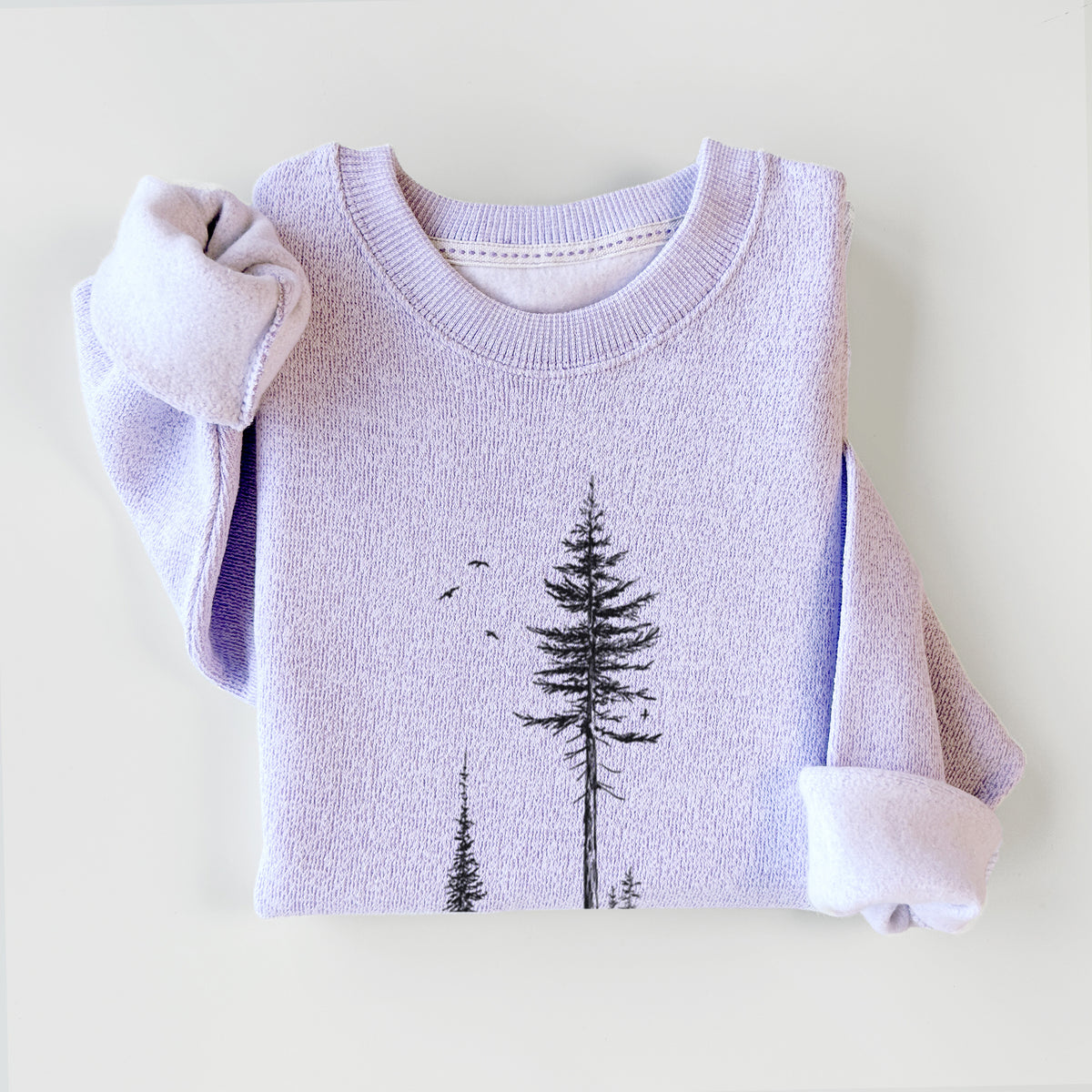 Ice purple knit sweatshirt printed with a black ink illustration of a lone hiker walking between tall pine trees with birds overhead, styled flat.
