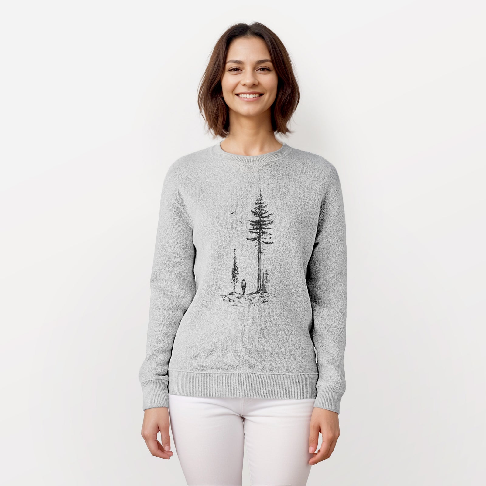 Salt and pepper knit sweatshirt laid flat, printed with a black ink illustration of a lone hiker walking between tall pine trees with birds overhead.
