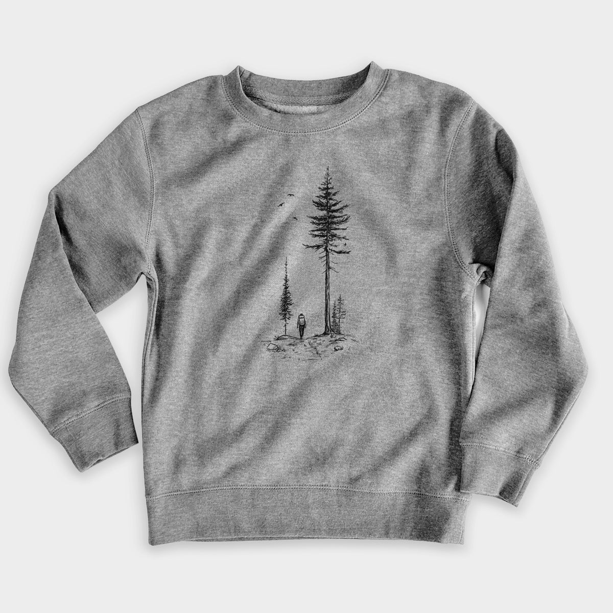 Nickel grey youth crewneck sweatshirt laid flat, printed with a black ink illustration of a lone hiker walking between tall pine trees with birds overhead.