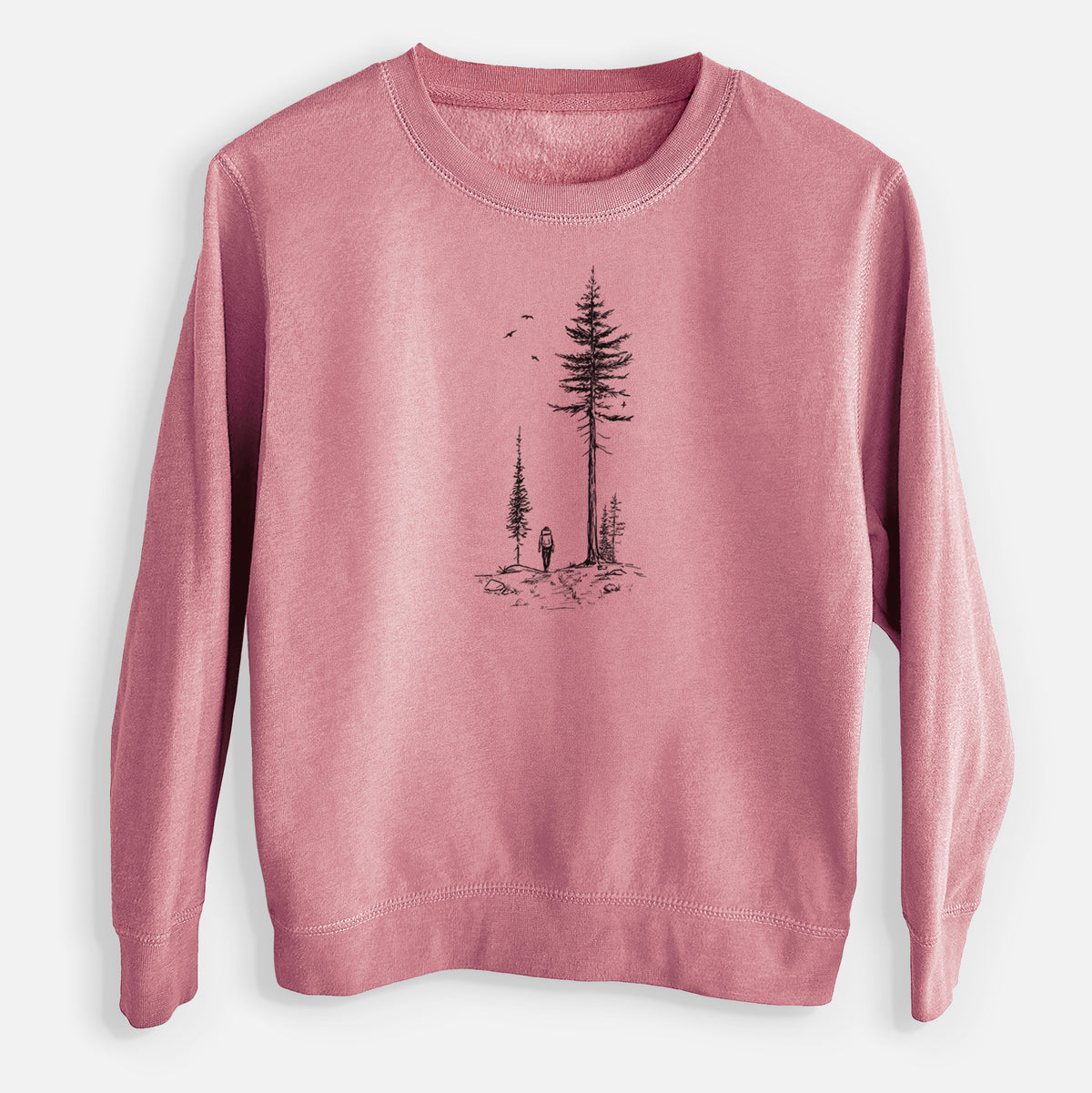 Mauve pink youth crewneck sweatshirt laid flat, printed with a black ink illustration of a lone hiker walking between tall pine trees with birds overhead.
