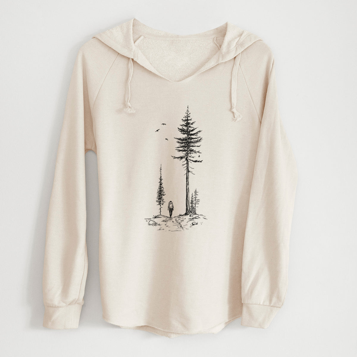 Bone cream women's Cali Wave hooded sweatshirt laid flat, printed with a black ink illustration of a lone hiker walking between tall pine trees with birds overhead.