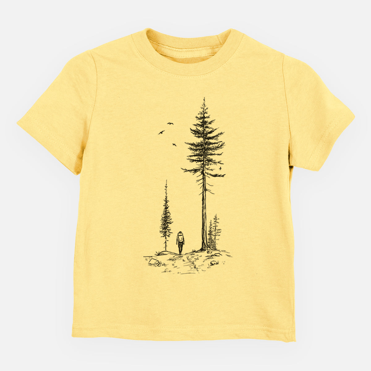 Butter yellow toddler t-shirt laid flat, printed with a black ink illustration of a lone hiker walking between tall pine trees with birds overhead.