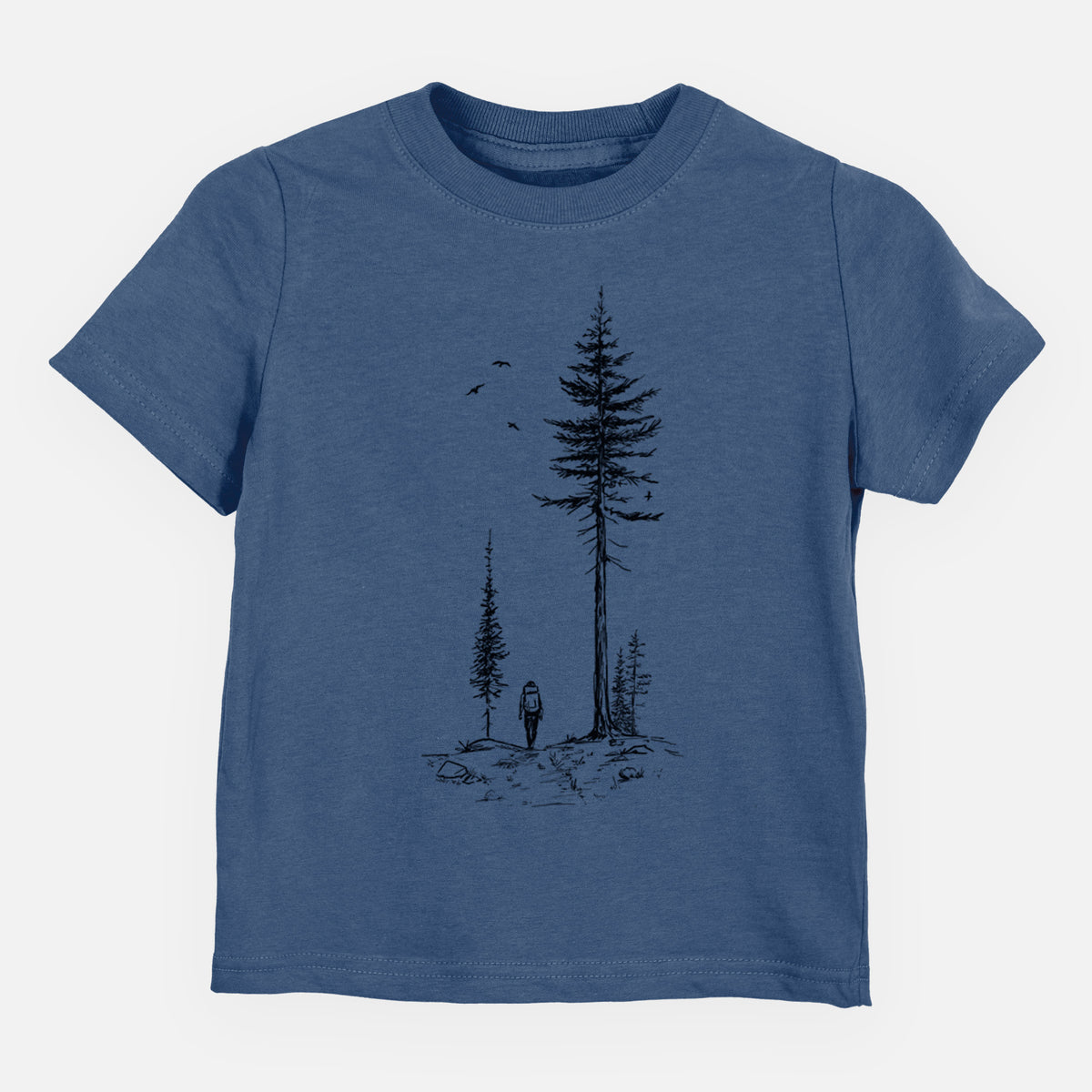 Indigo blue toddler t-shirt laid flat, printed with a black ink illustration of a lone hiker walking between tall pine trees with birds overhead.