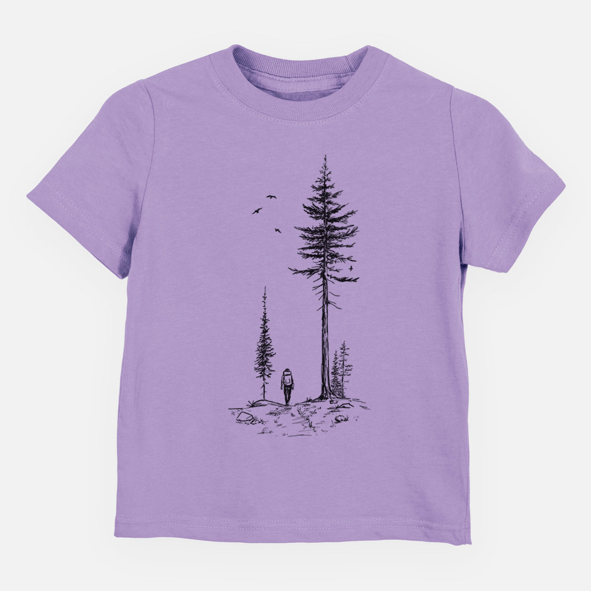 Lavender toddler t-shirt laid flat, printed with a black ink illustration of a lone hiker walking between tall pine trees with birds overhead.