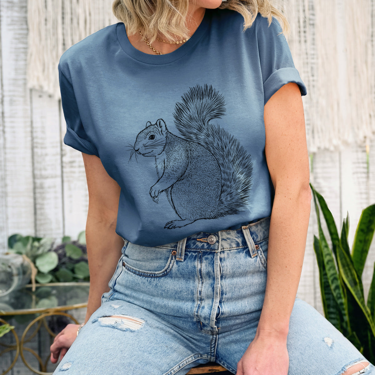 Woman wearing a steel blue lightweight cotton t-shirt printed with a detailed black ink illustration of a fox squirrel sitting with a bushy tail.