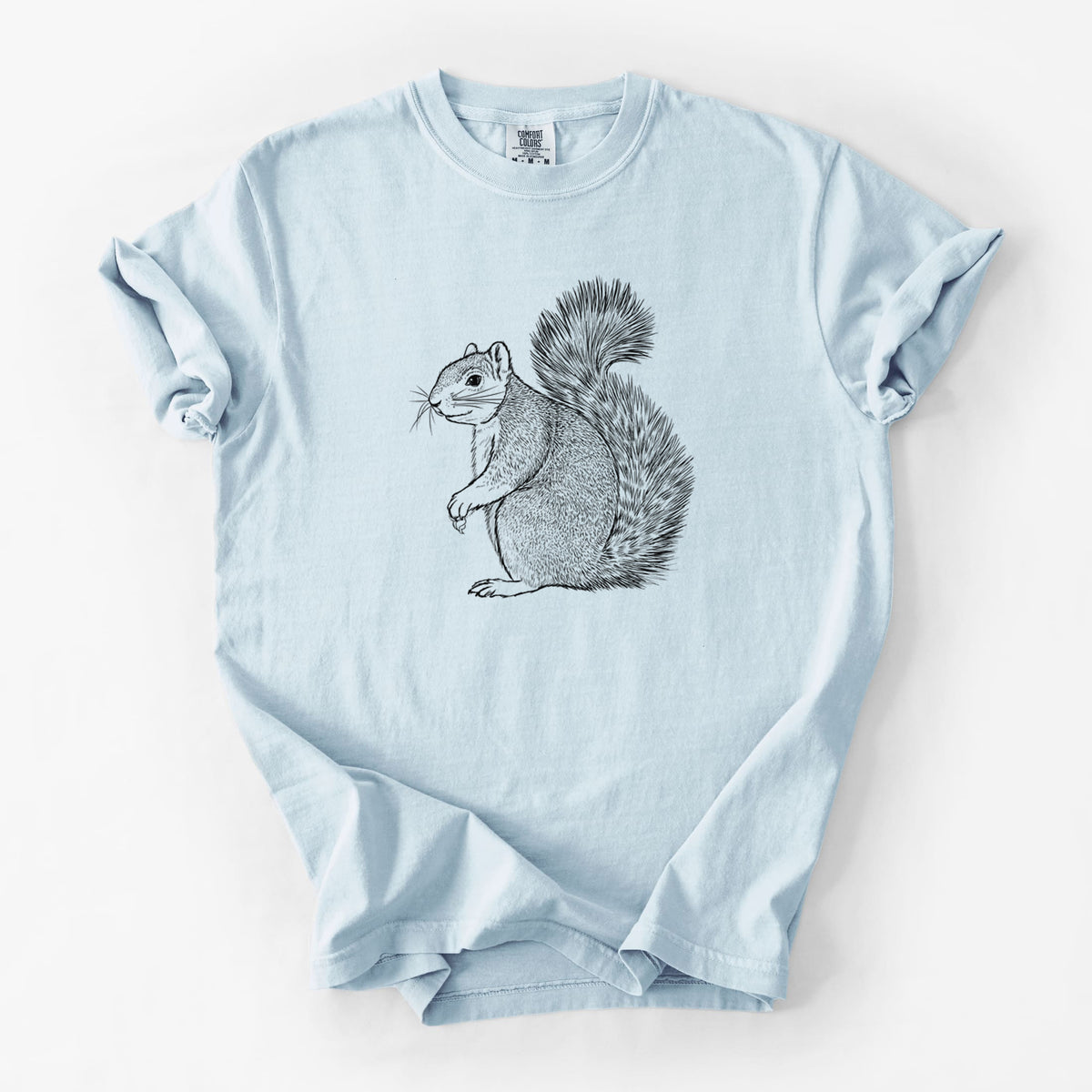 Chambray blue Comfort Colors t-shirt laid flat, printed with a detailed black ink illustration of a fox squirrel sitting with a bushy tail.