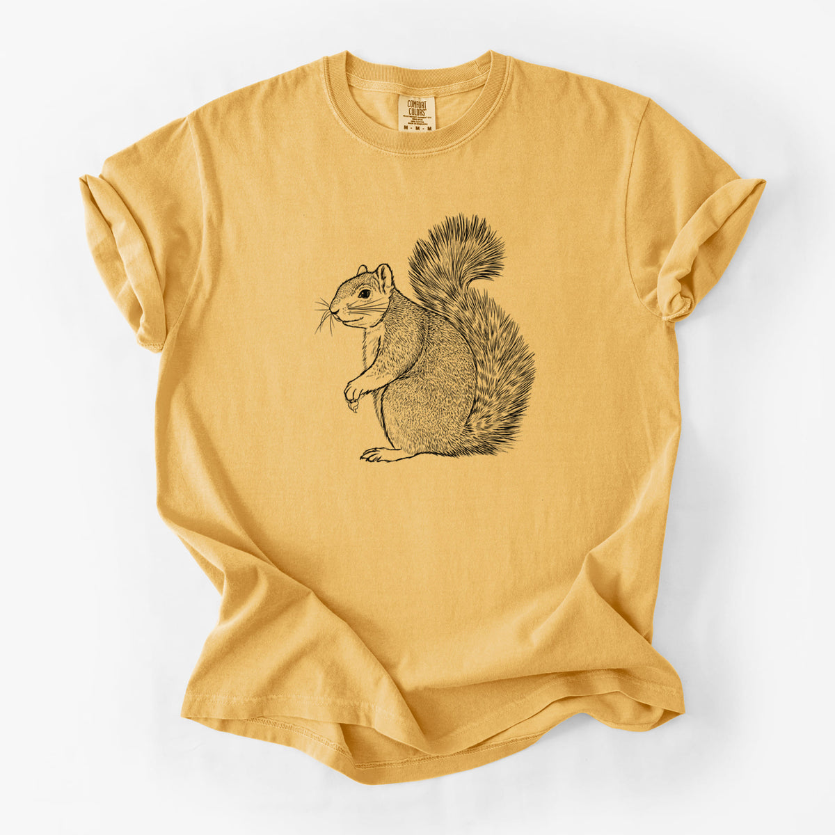Golden wheat yellow Comfort Colors t-shirt laid flat, printed with a detailed black ink illustration of a fox squirrel sitting with a bushy tail.