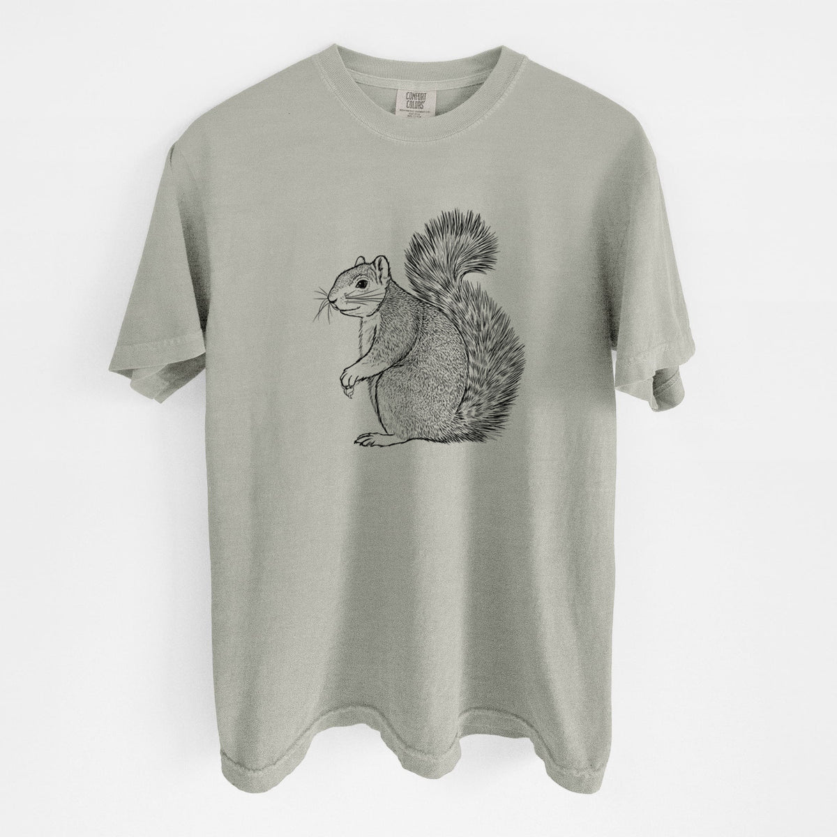 Sandstone beige Comfort Colors t-shirt laid flat, printed with a detailed black ink illustration of a fox squirrel sitting with a bushy tail.