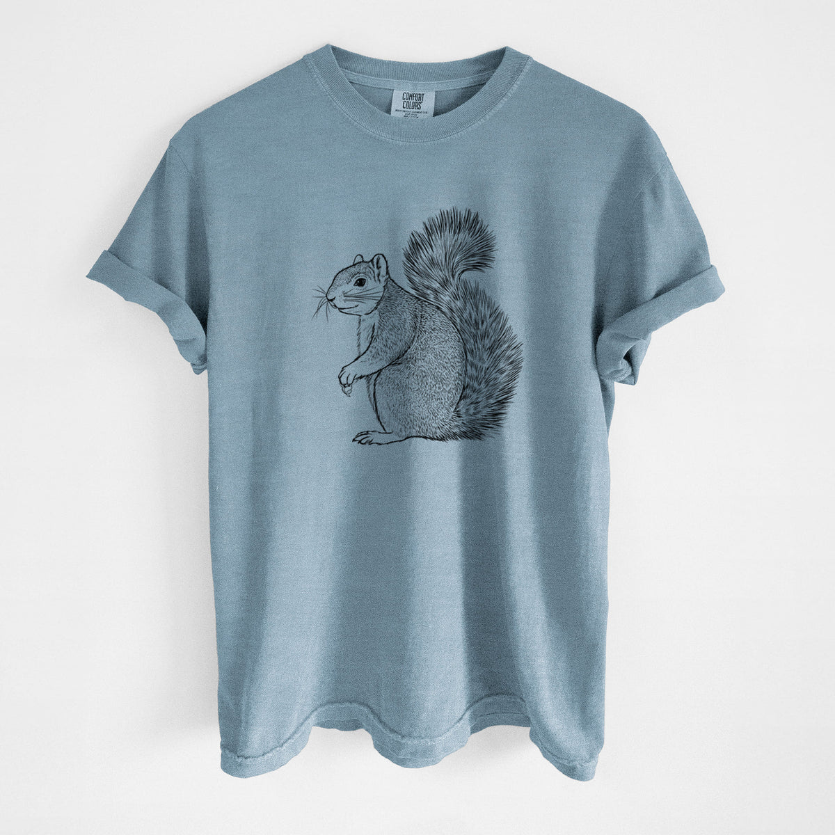 Steel blue Comfort Colors t-shirt laid flat, printed with a detailed black ink illustration of a fox squirrel sitting with a bushy tail.