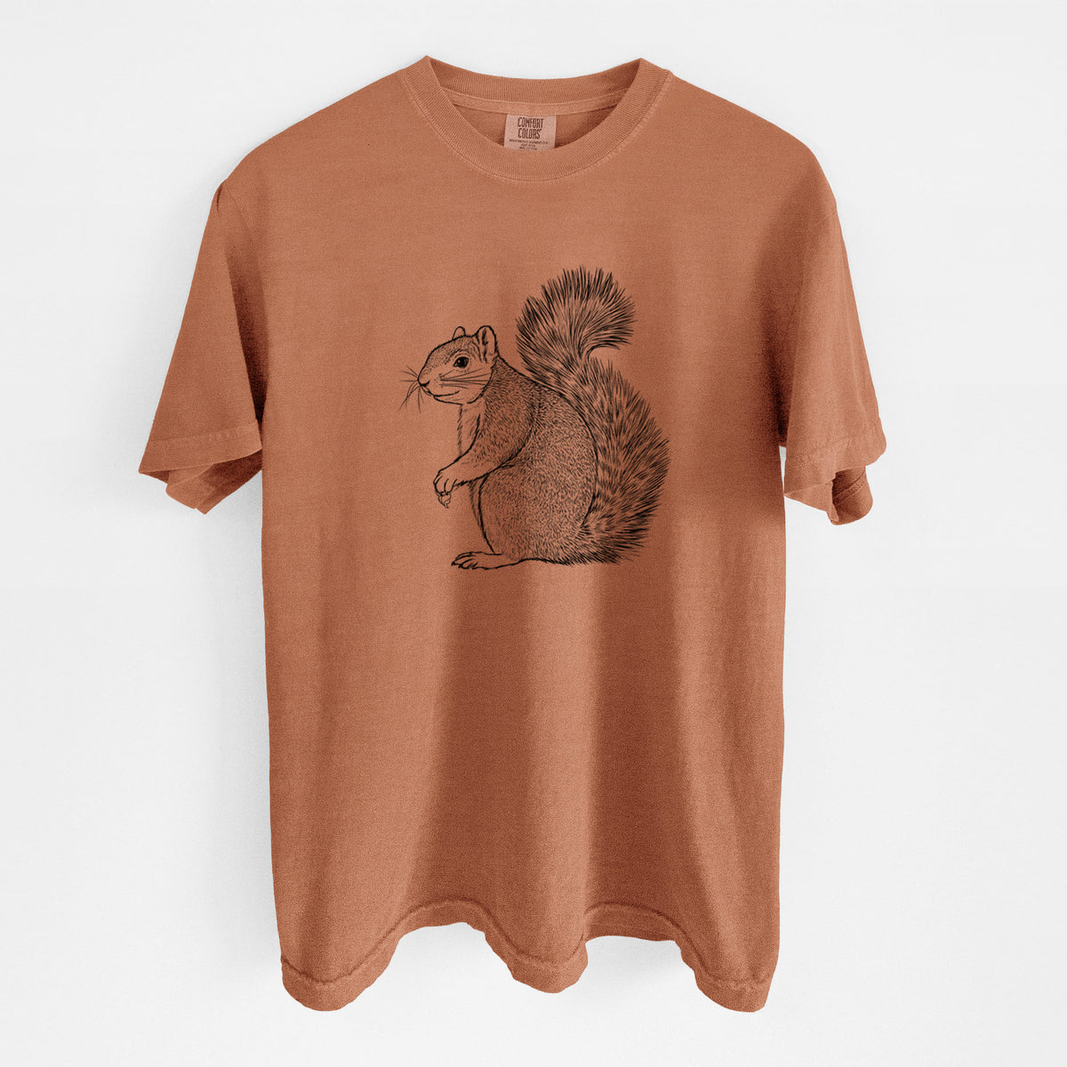 Yam burnt orange Comfort Colors t-shirt laid flat, printed with a detailed black ink illustration of a fox squirrel sitting with a bushy tail.