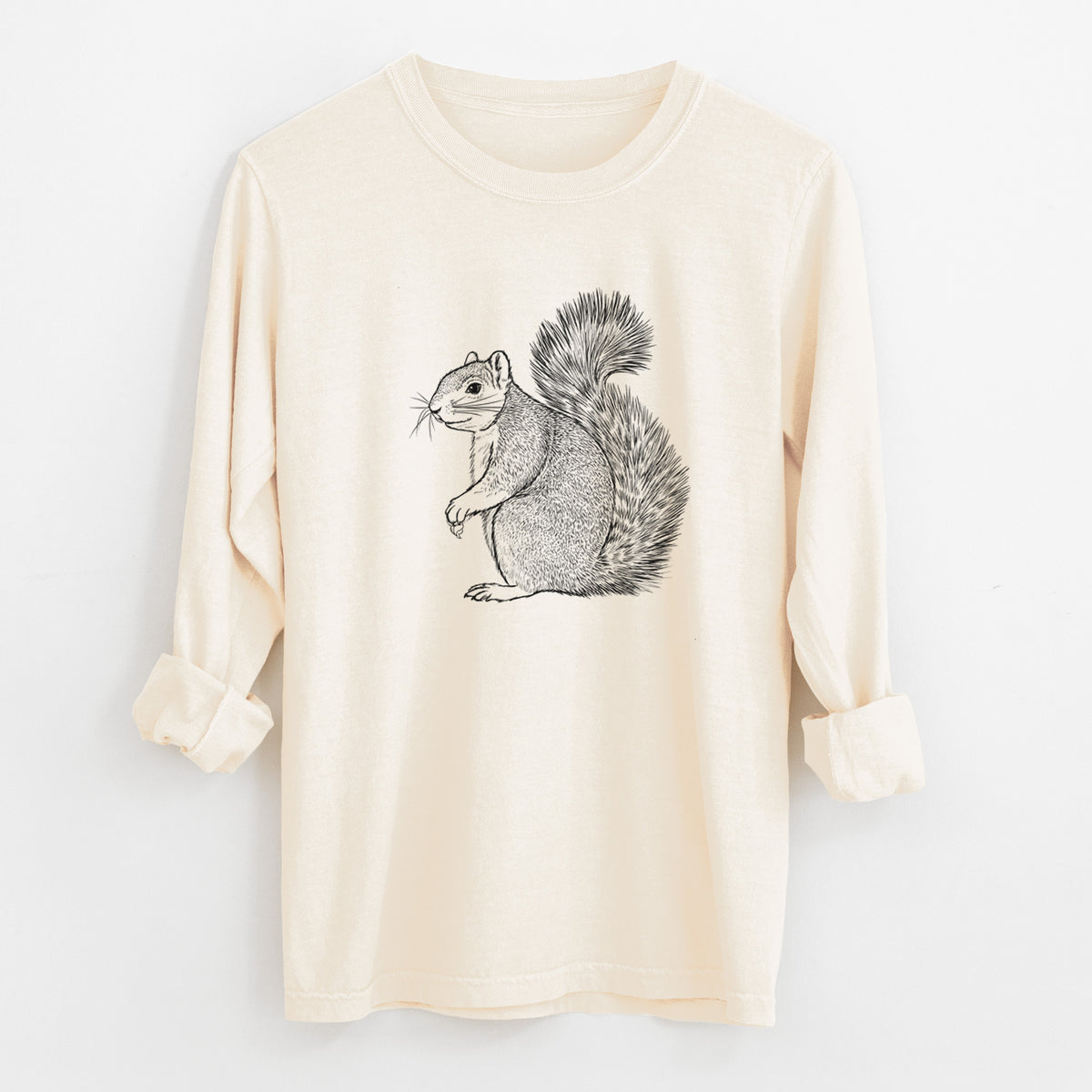 Ivory Comfort Colors long sleeve shirt laid flat with the cuffs rolled, printed with a detailed black ink illustration of a fox squirrel sitting with a bushy tail.