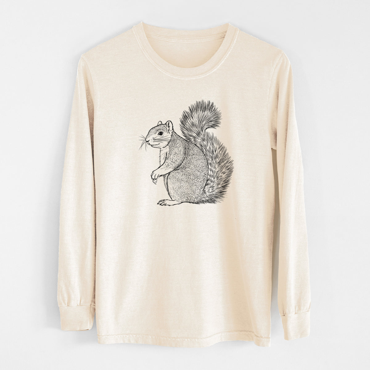 Ivory Comfort Colors long sleeve shirt laid flat, printed with a detailed black ink illustration of a fox squirrel sitting with a bushy tail.