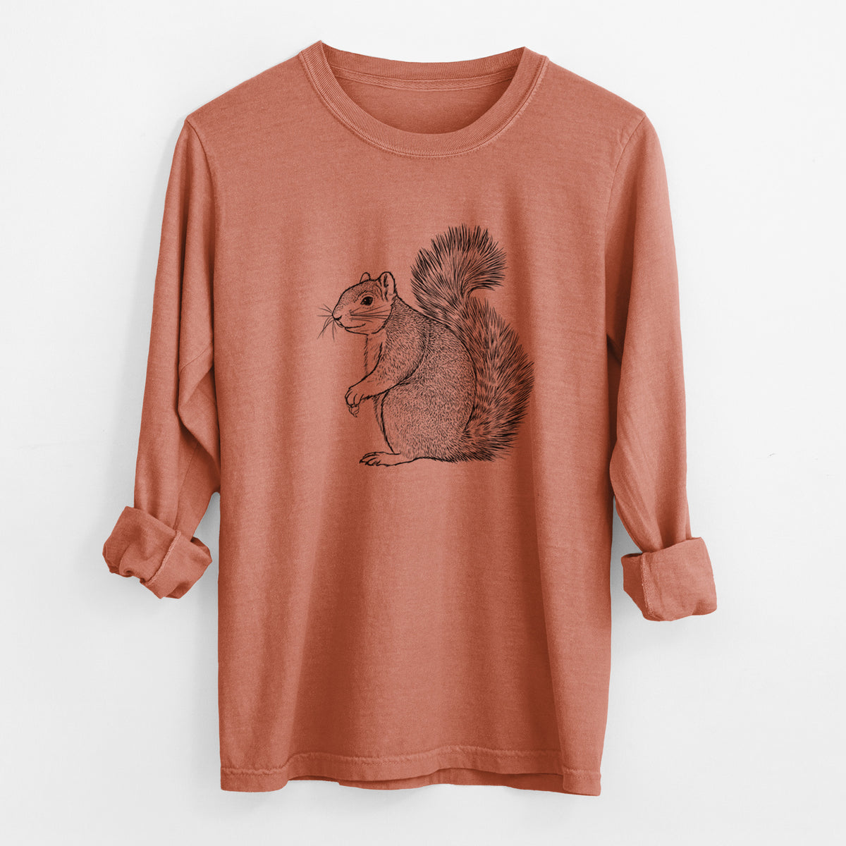 Yam burnt orange Comfort Colors long sleeve shirt laid flat with the cuffs rolled, printed with a detailed black ink illustration of a fox squirrel sitting with a bushy tail.
