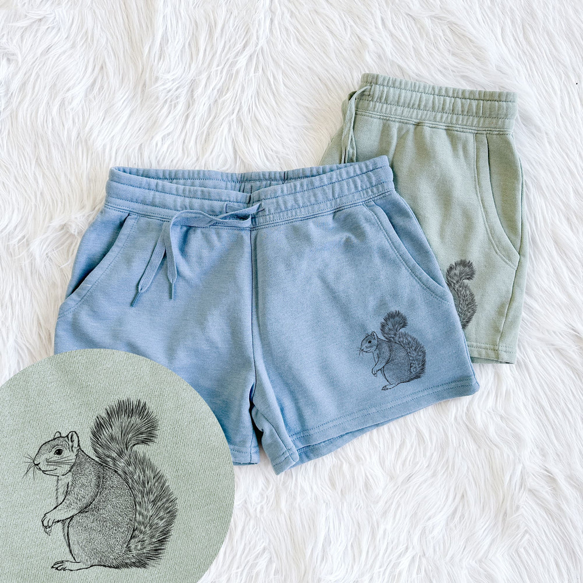Two pairs of Cali Wave shorts in different colors printed with a detailed black ink illustration of a fox squirrel sitting with a bushy tail, with a close-up of the print.