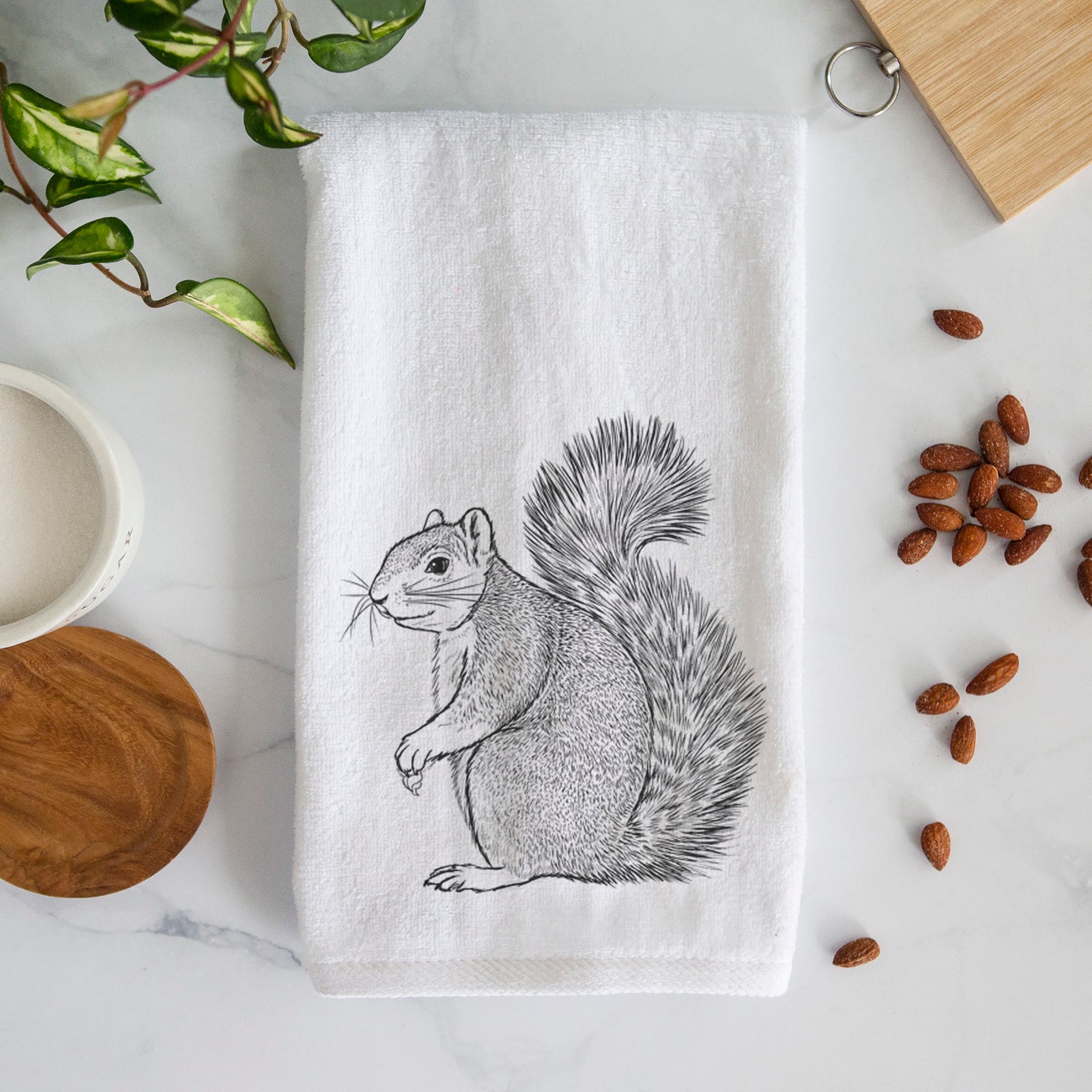 White hand towel printed with a detailed black ink illustration of a fox squirrel sitting with a bushy tail.