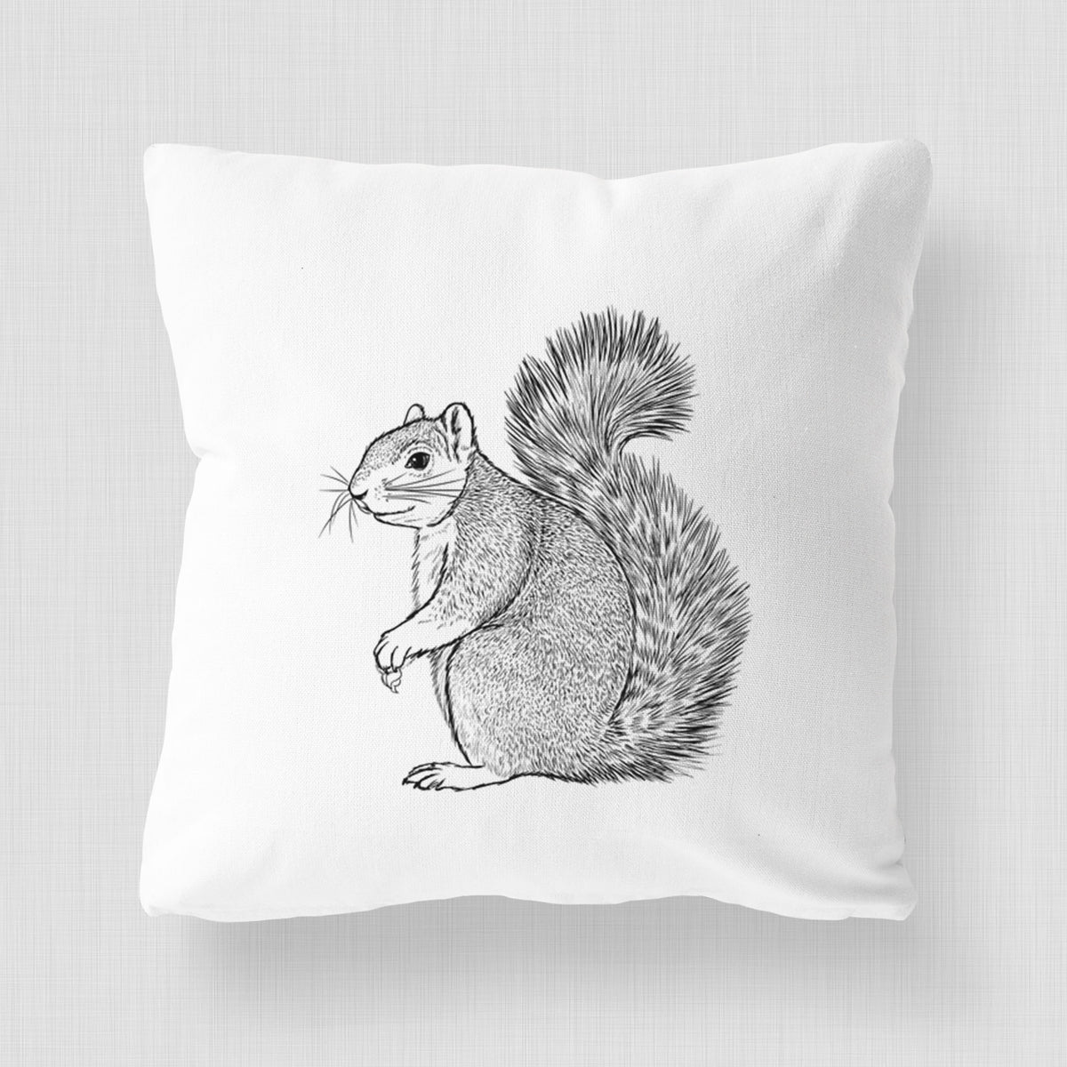 White pillow cover printed with a detailed black ink illustration of a fox squirrel sitting with a bushy tail.