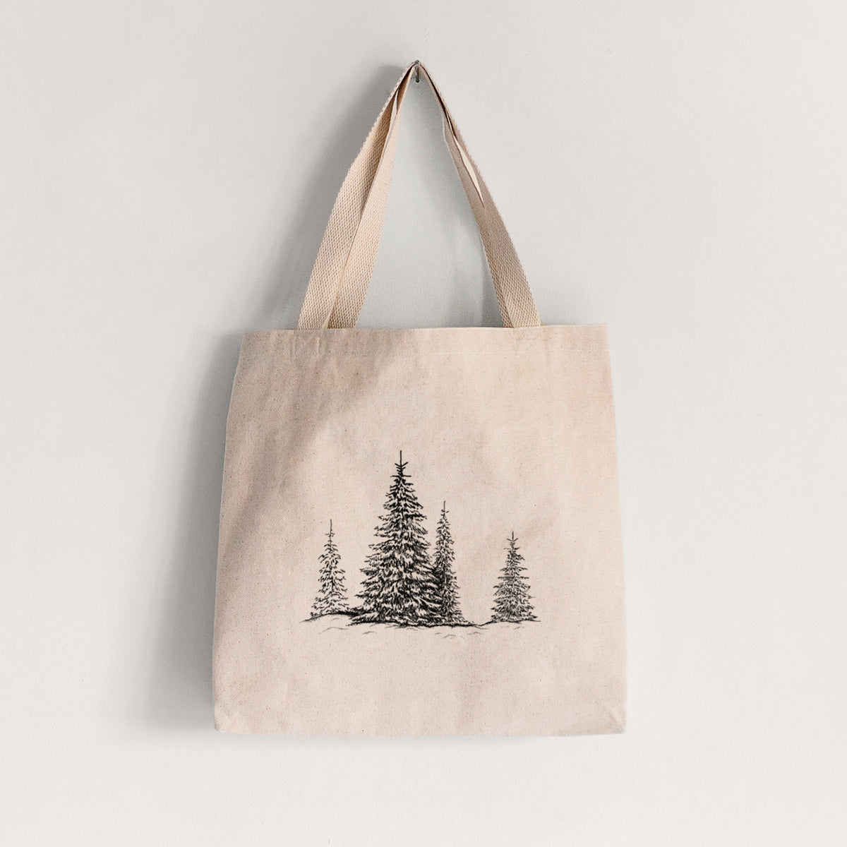 Natural canvas tote bag printed with a black ink illustration of frost-covered evergreen trees.