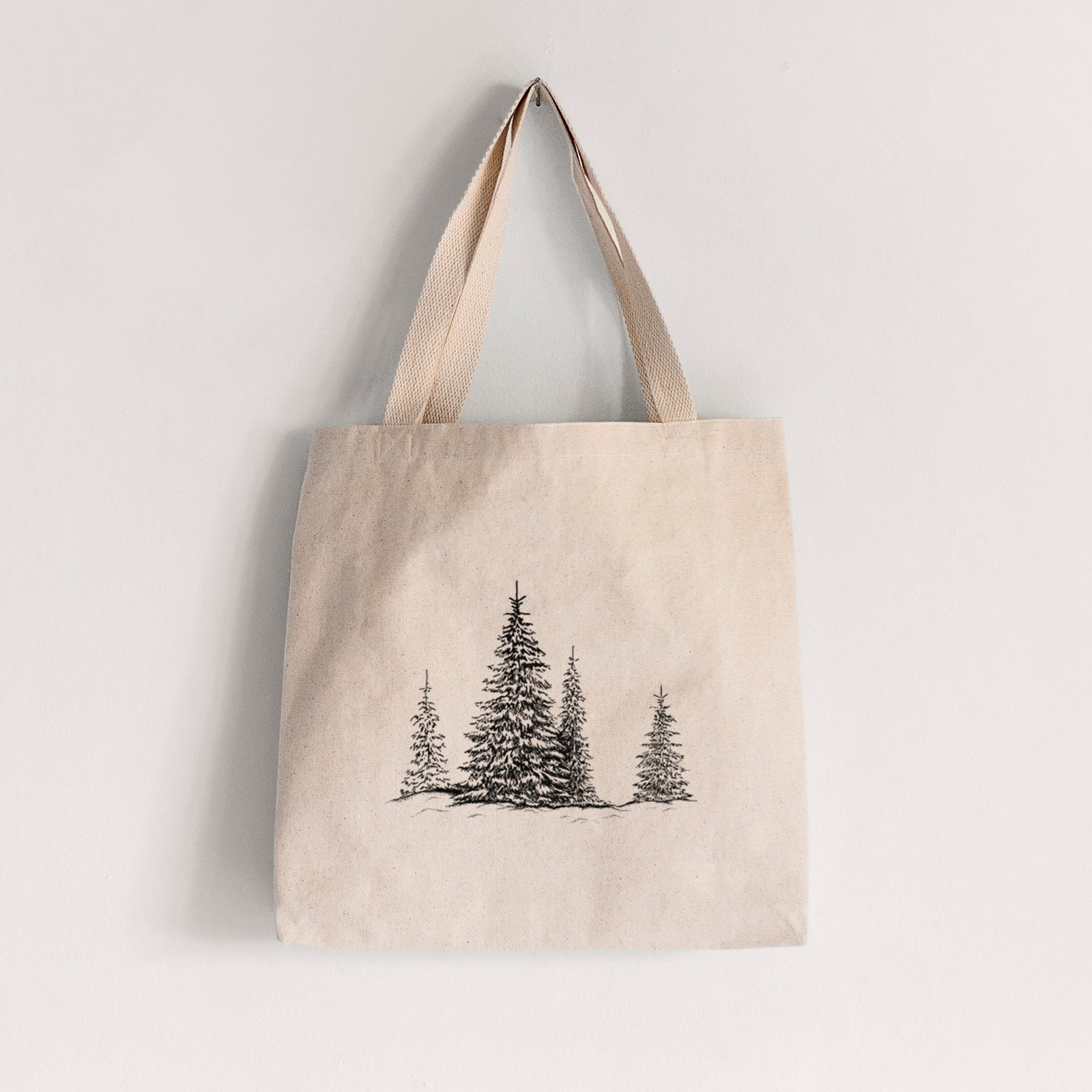 Natural canvas tote bag printed with a black ink illustration of frost-covered evergreen trees.