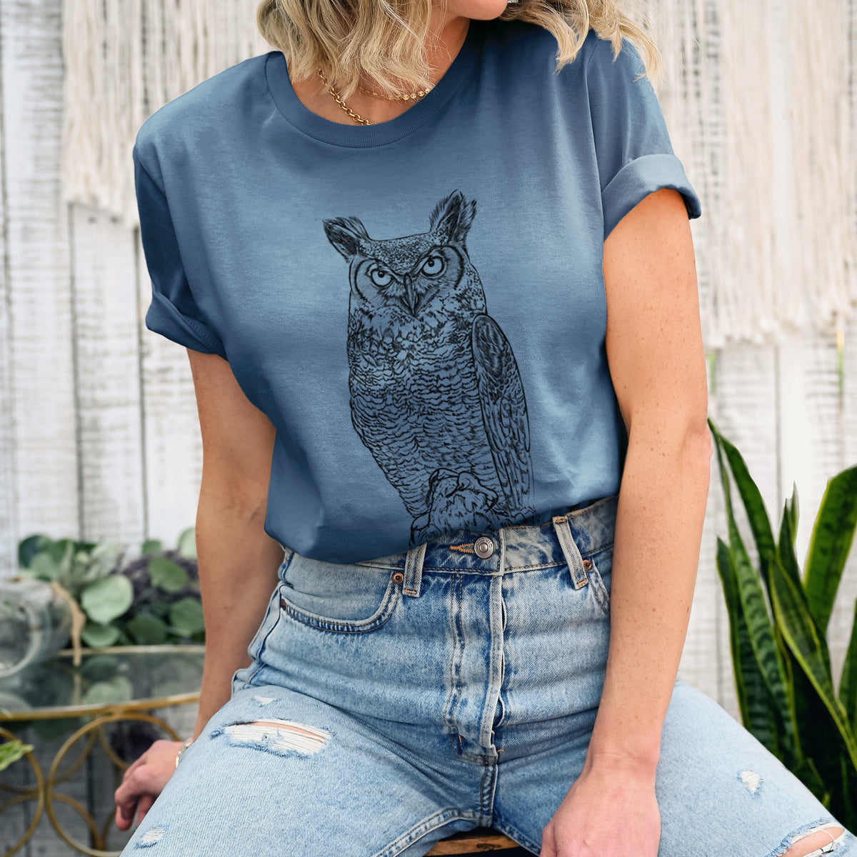 Woman wearing a steel blue lightweight cotton t-shirt printed with a detailed black ink illustration of a great horned owl standing upright with its ear tufts raised.