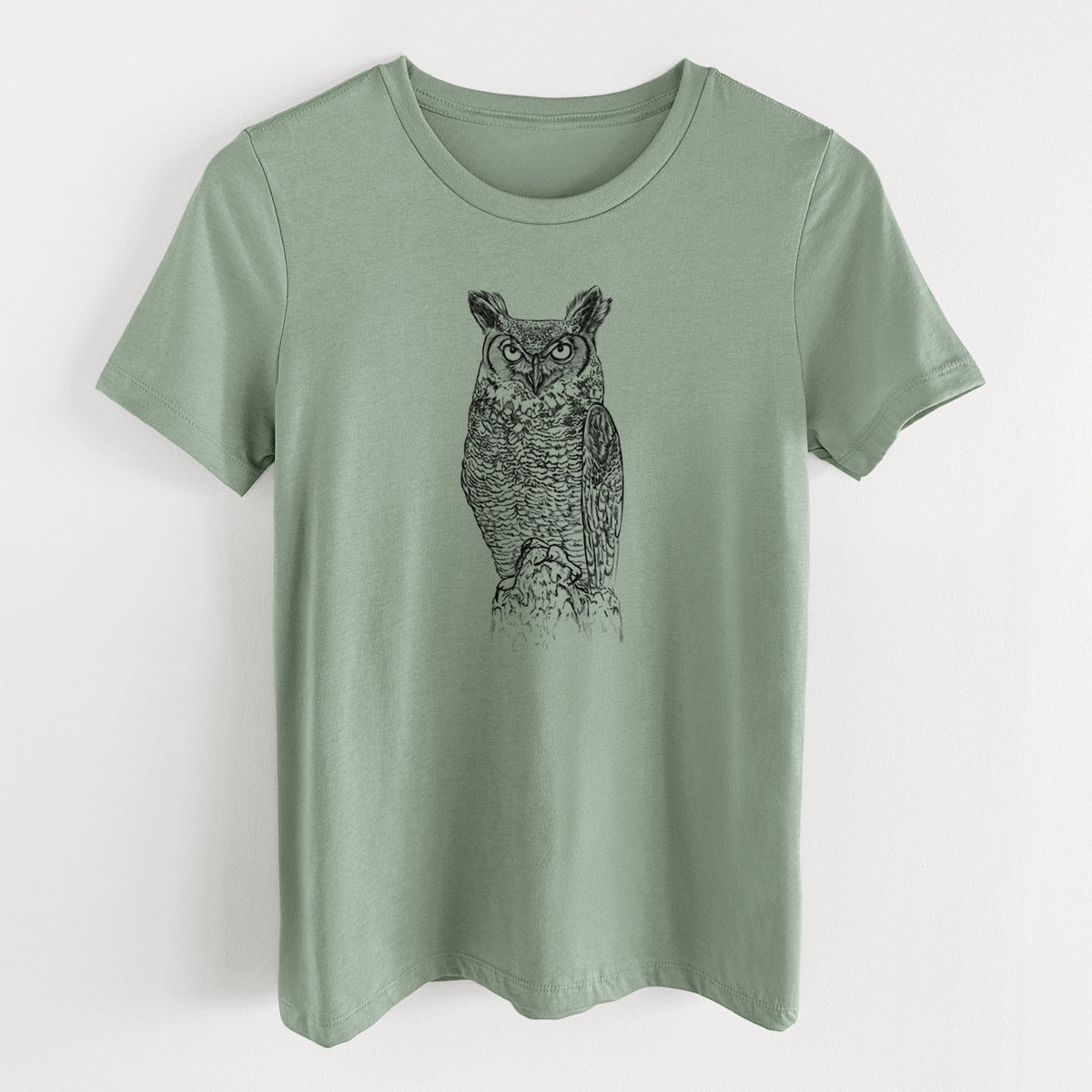 Sage green women's relaxed fit cotton t-shirt laid flat, printed with a detailed black ink illustration of a great horned owl standing upright with its ear tufts raised.
