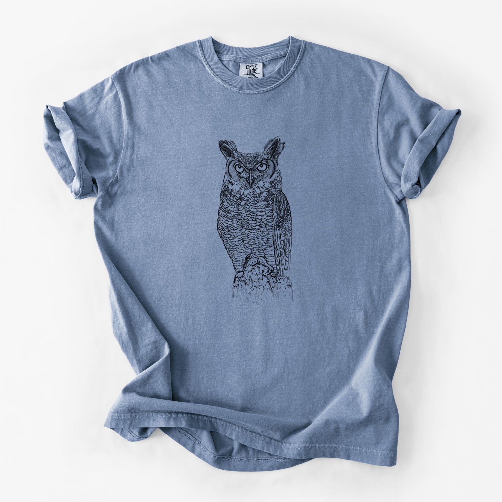 Blue jean Comfort Colors t-shirt laid flat, printed with a detailed black ink illustration of a great horned owl standing upright with its ear tufts raised.