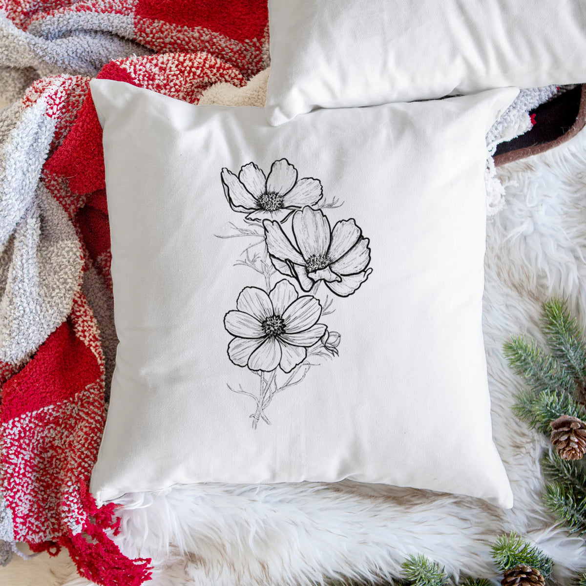 White pillow cover printed with a black ink line drawing of garden cosmos flowers on stems, on a woven chair.