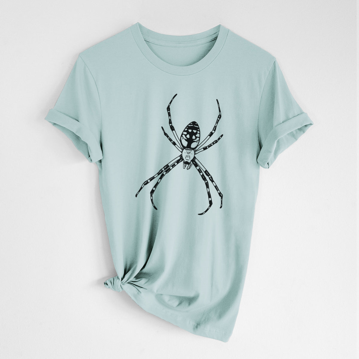 Dusty blue lightweight cotton t-shirt laid flat with the sleeves rolled, printed with a detailed black ink illustration of a garden spider with long striped legs.