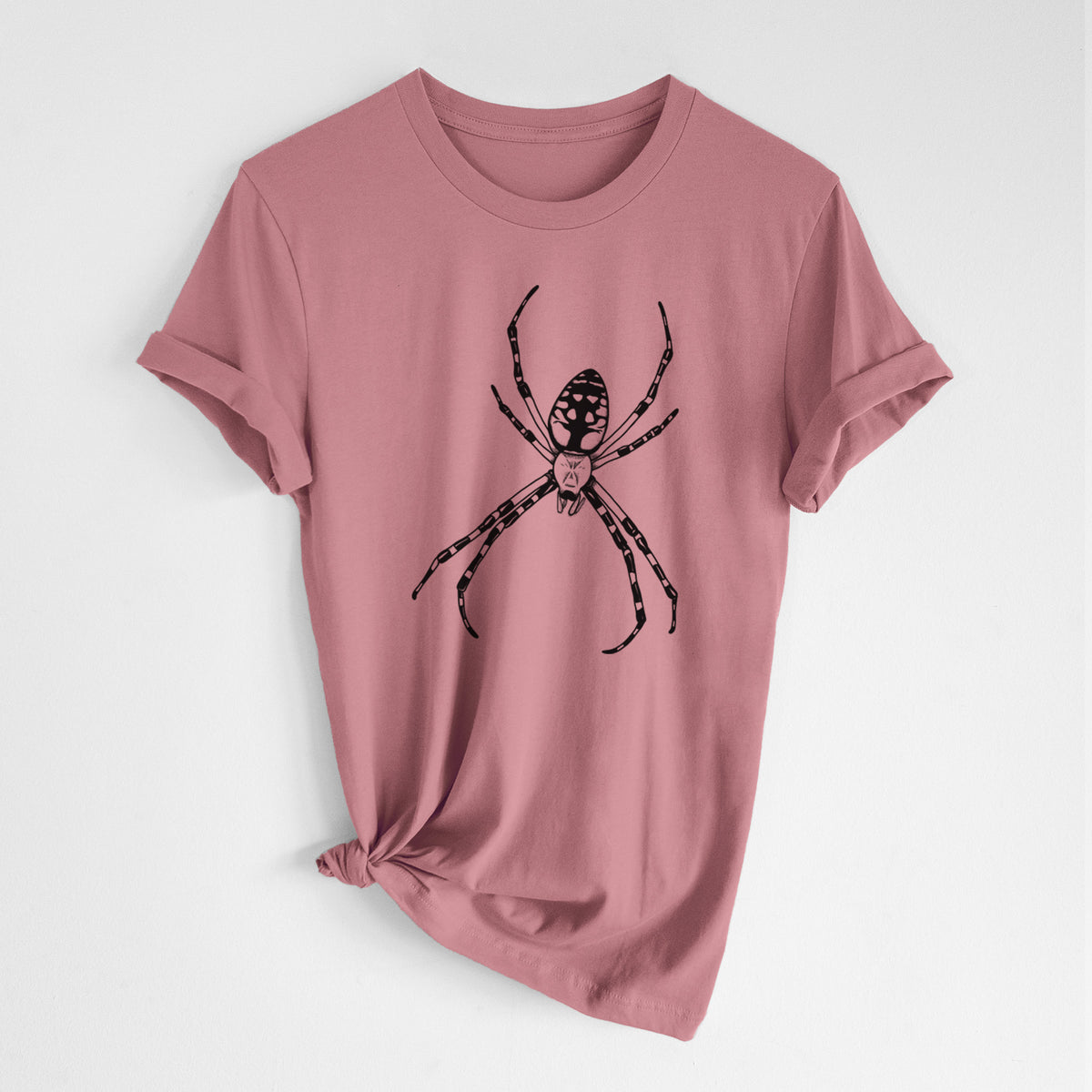 Mauve pink lightweight cotton t-shirt laid flat with the sleeves rolled, printed with a detailed black ink illustration of a garden spider with long striped legs.