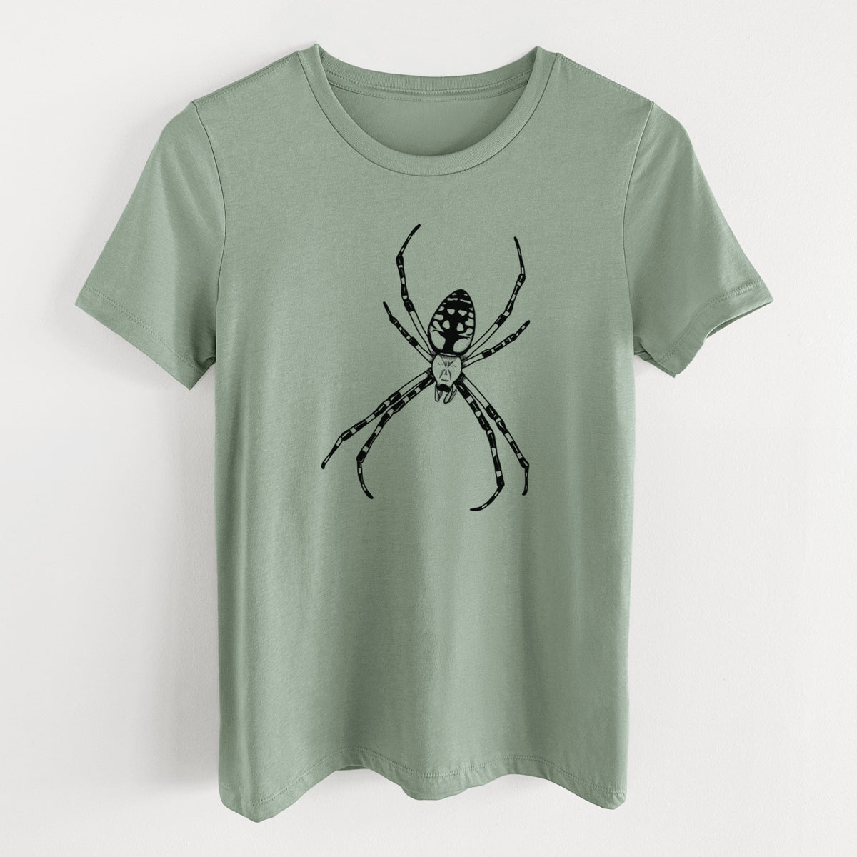 Sage green women's relaxed fit cotton t-shirt laid flat, printed with a detailed black ink illustration of a garden spider with long striped legs.