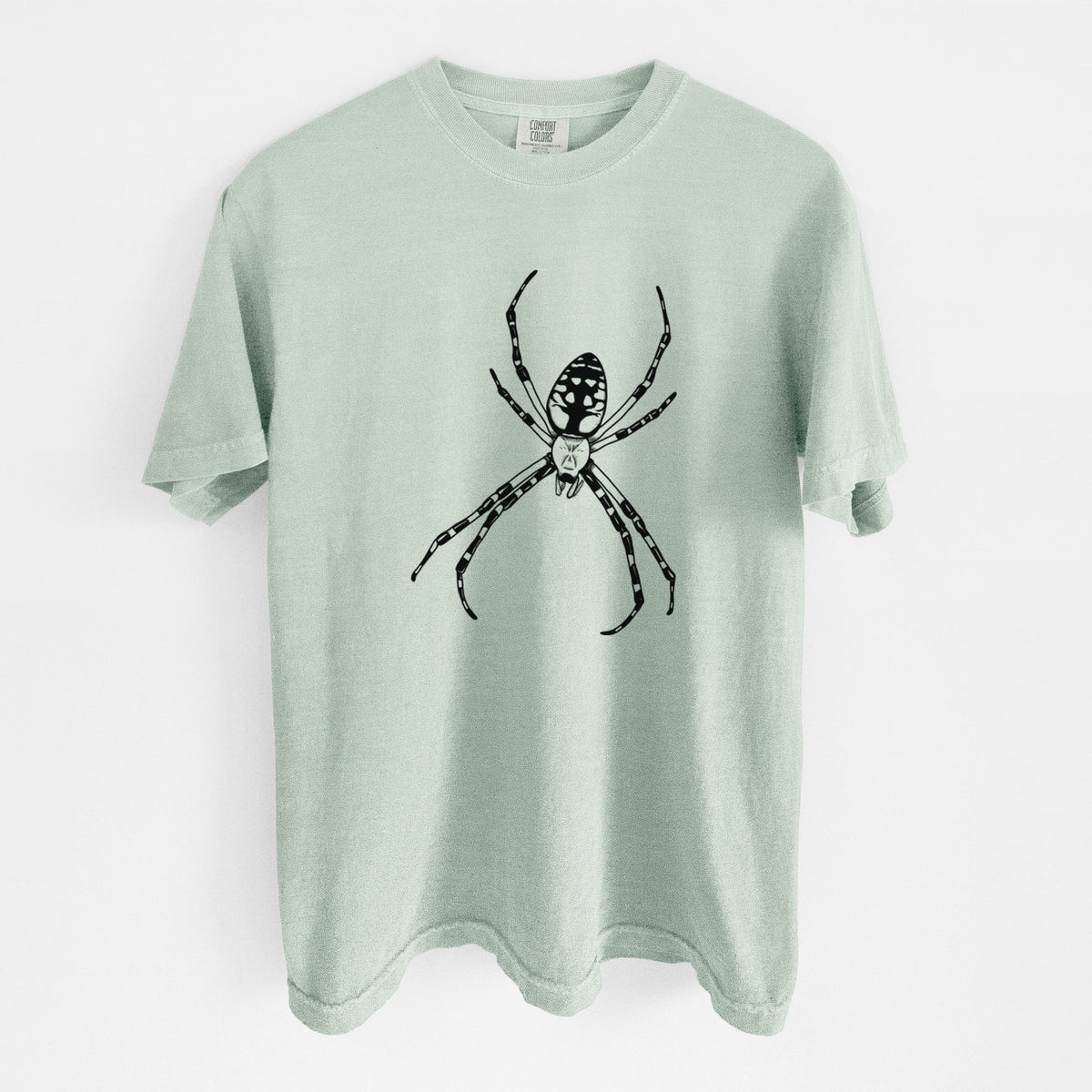 Bay green Comfort Colors t-shirt laid flat, printed with a detailed black ink illustration of a garden spider with long striped legs.