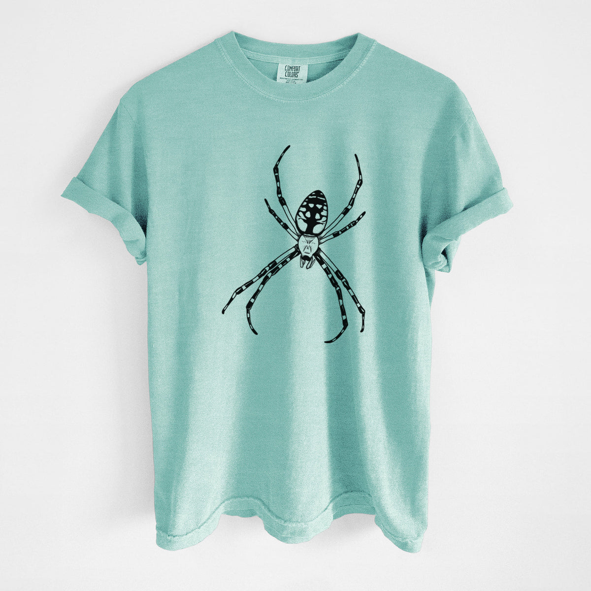 Chalky mint Comfort Colors t-shirt laid flat, printed with a detailed black ink illustration of a garden spider with long striped legs.