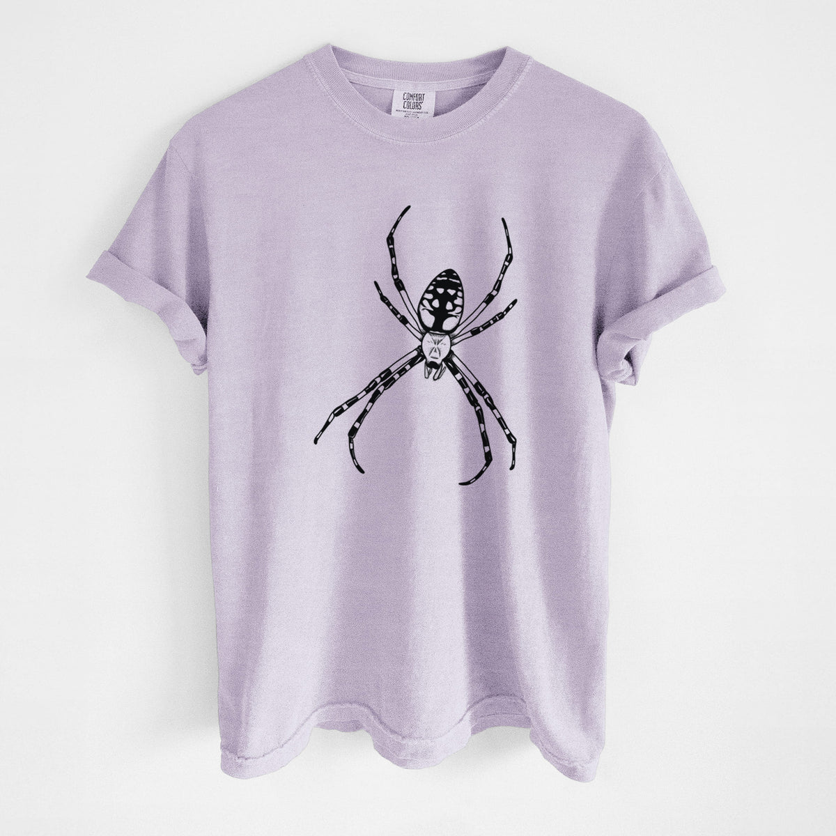Orchid purple Comfort Colors t-shirt laid flat, printed with a detailed black ink illustration of a garden spider with long striped legs.