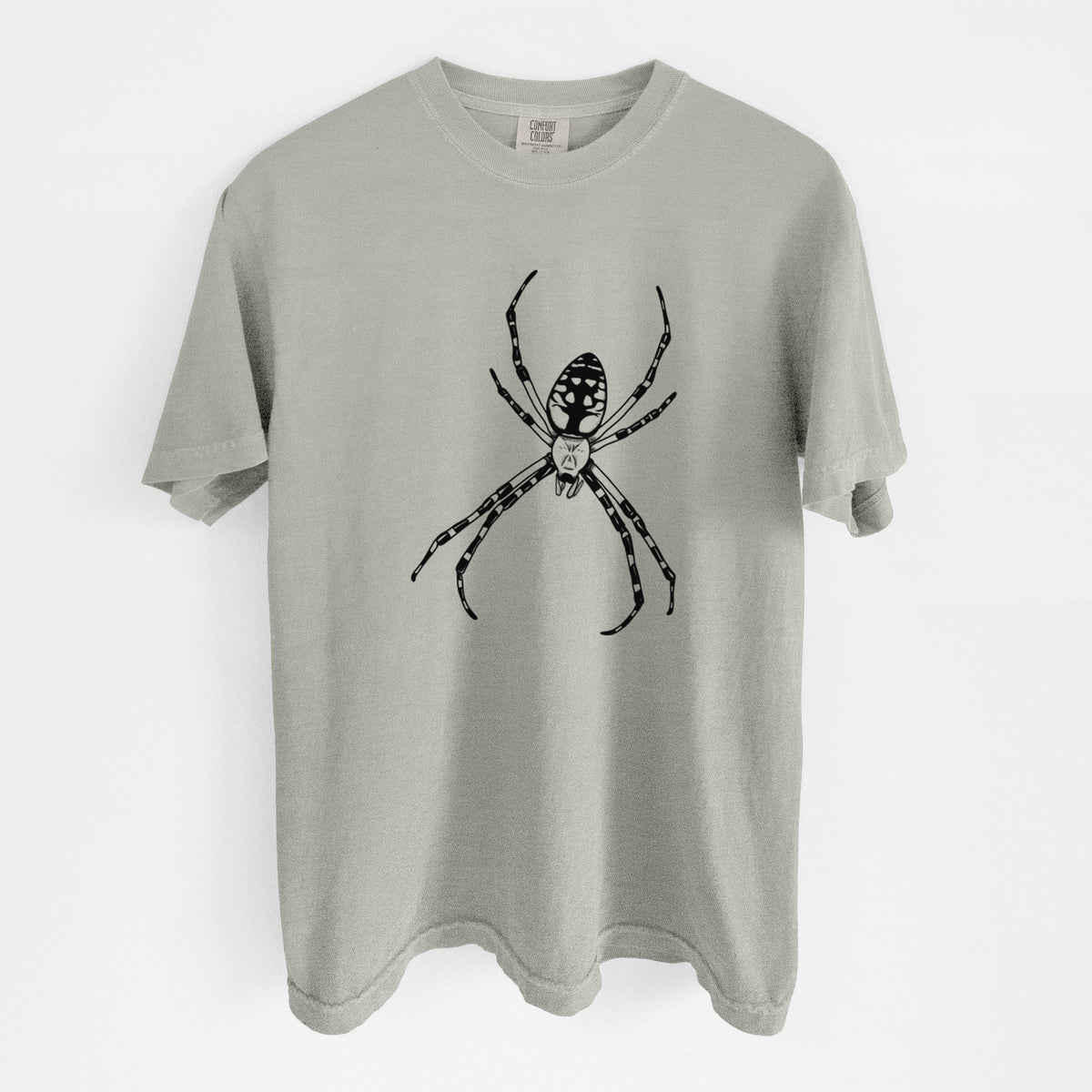 Sandstone beige Comfort Colors t-shirt laid flat, printed with a detailed black ink illustration of a garden spider with long striped legs.