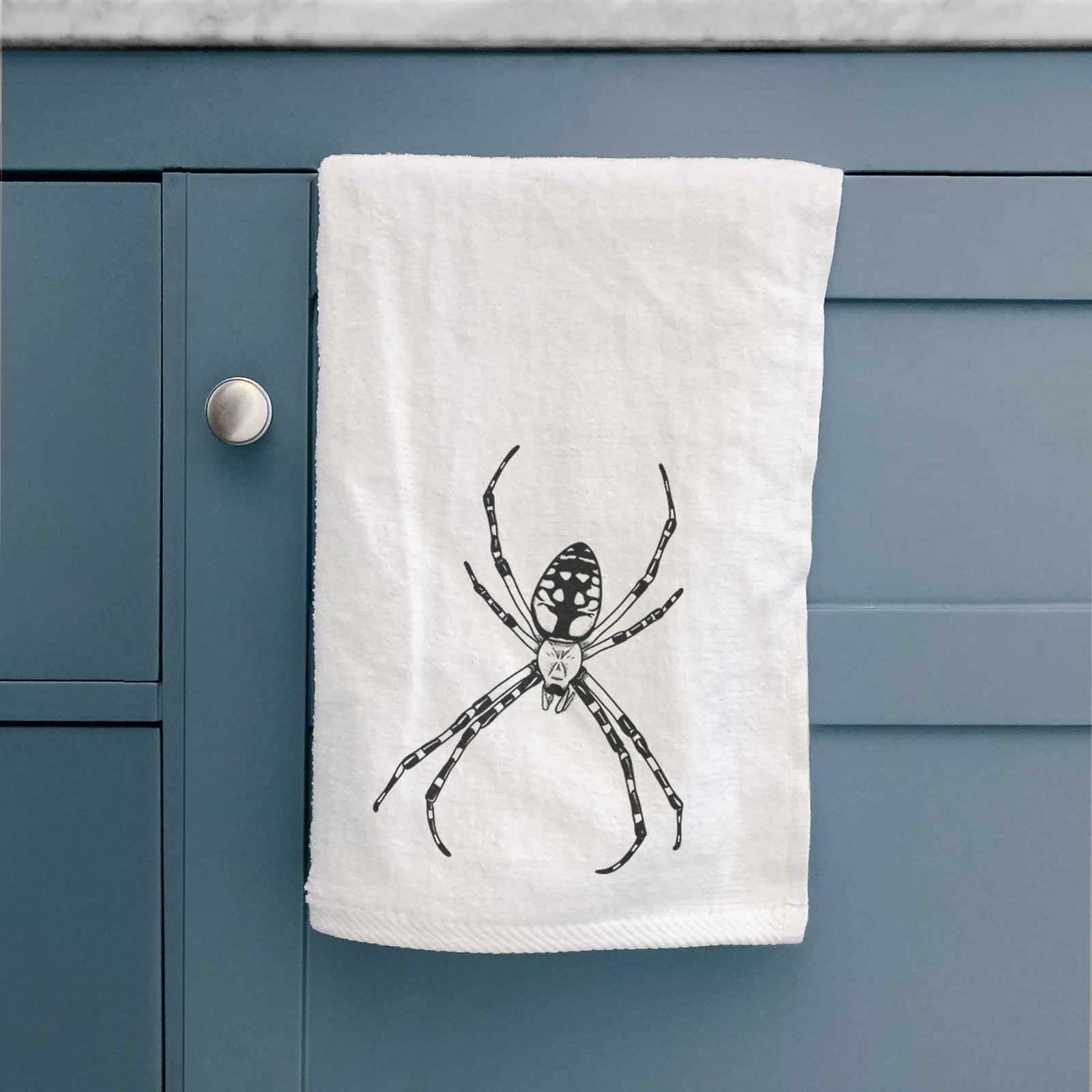 White hand towel printed with a detailed black ink illustration of a garden spider with long striped legs.