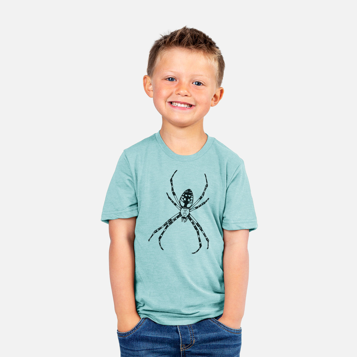 Smiling boy wearing a youth t-shirt printed with a detailed black ink illustration of a garden spider with long striped legs.