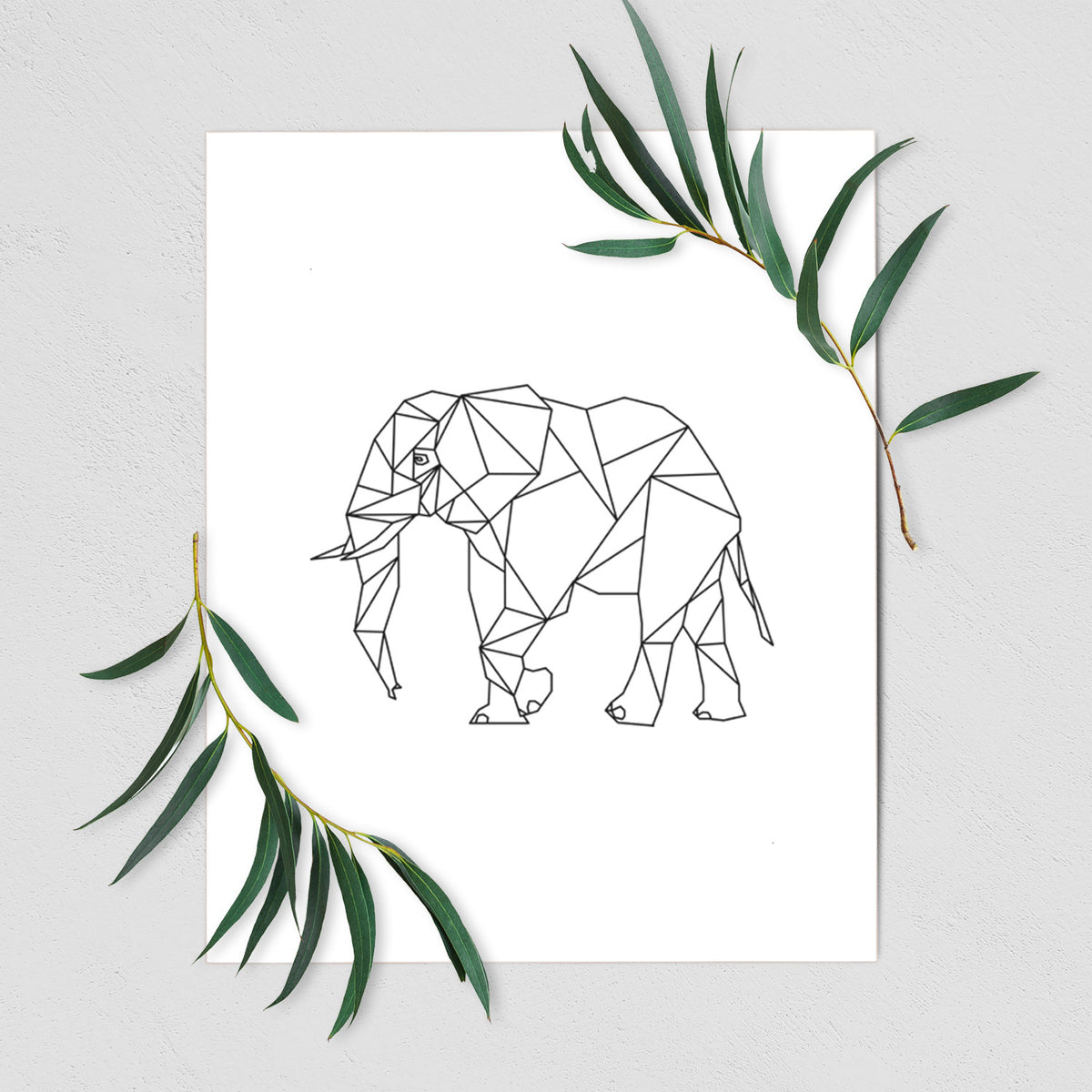 Art print of a black geometric line art elephant, shown with eucalyptus leaves.