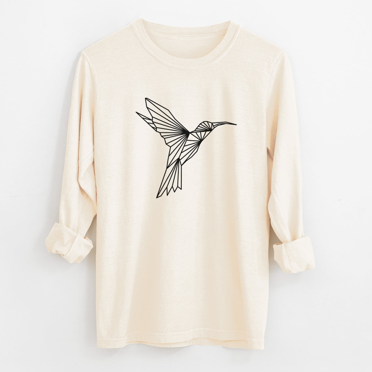 Ivory Comfort Colors long sleeve shirt laid flat with the cuffs rolled, printed with a black geometric line art hummingbird in flight.