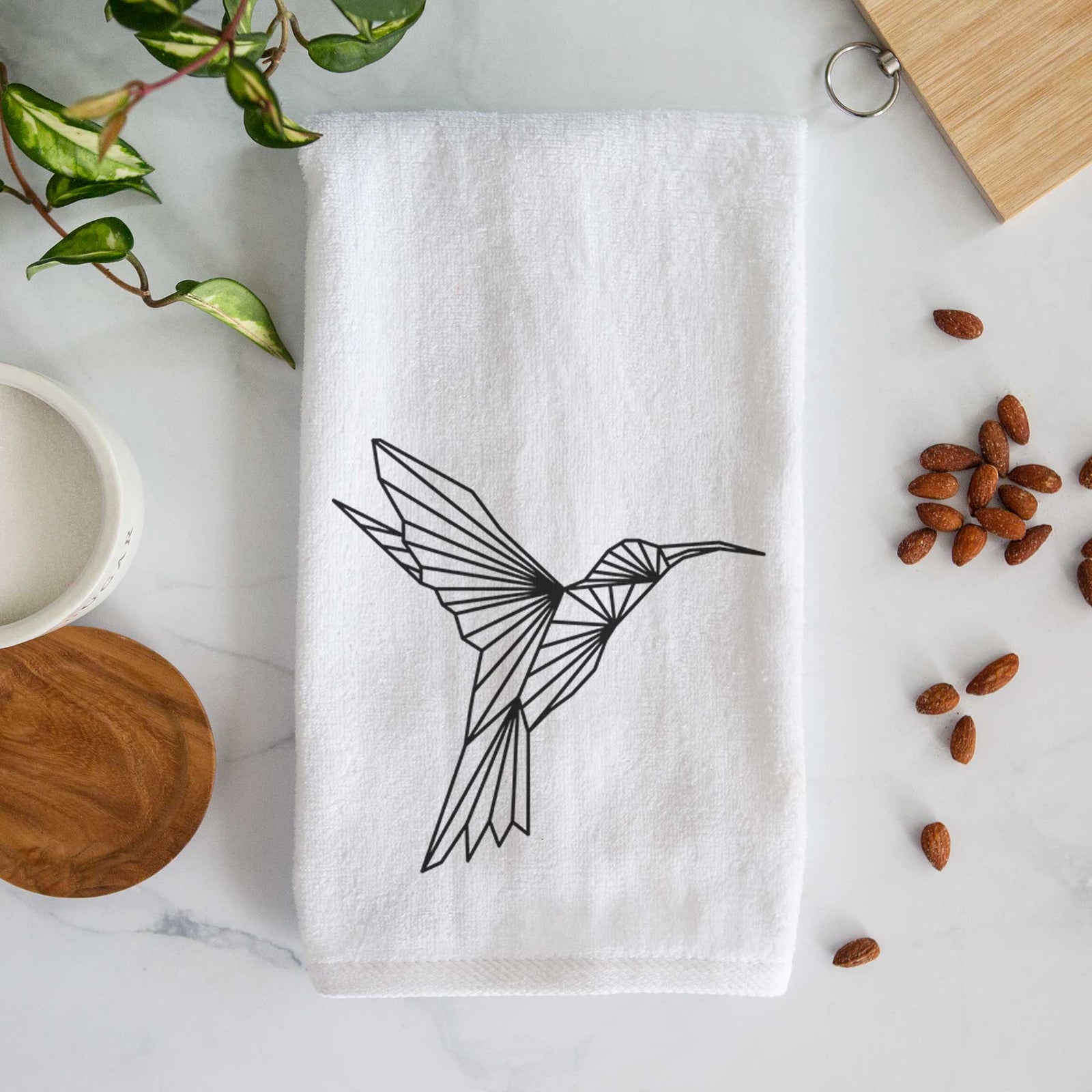 White hand towel printed with a black geometric line art hummingbird in flight.