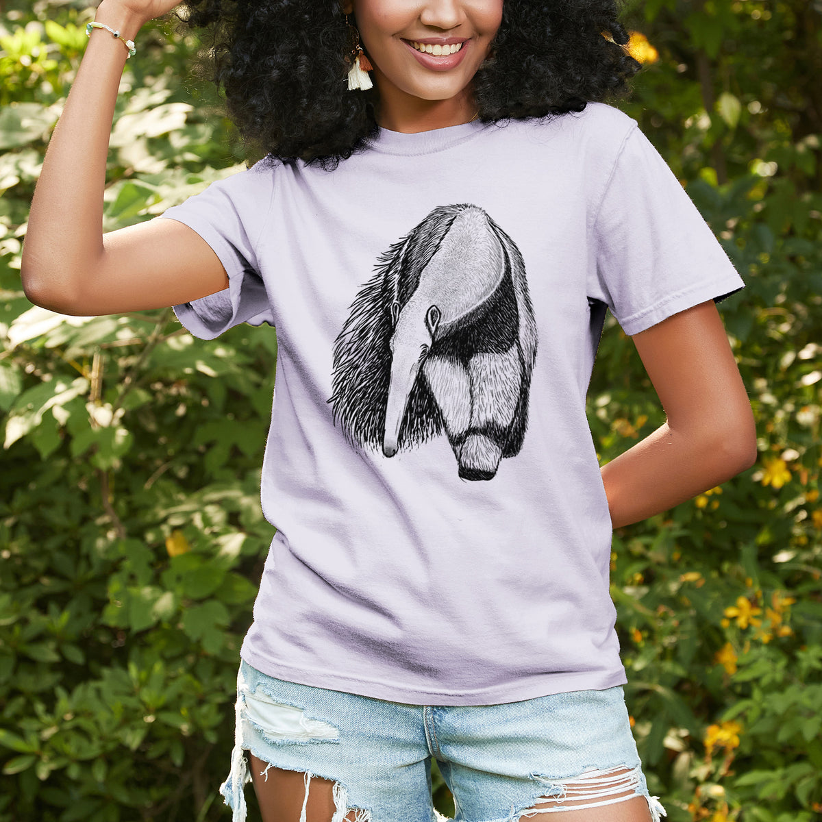 Woman wearing a Comfort Colors t-shirt printed with a detailed black ink illustration of a giant anteater with its long snout and bushy tail, outdoors.