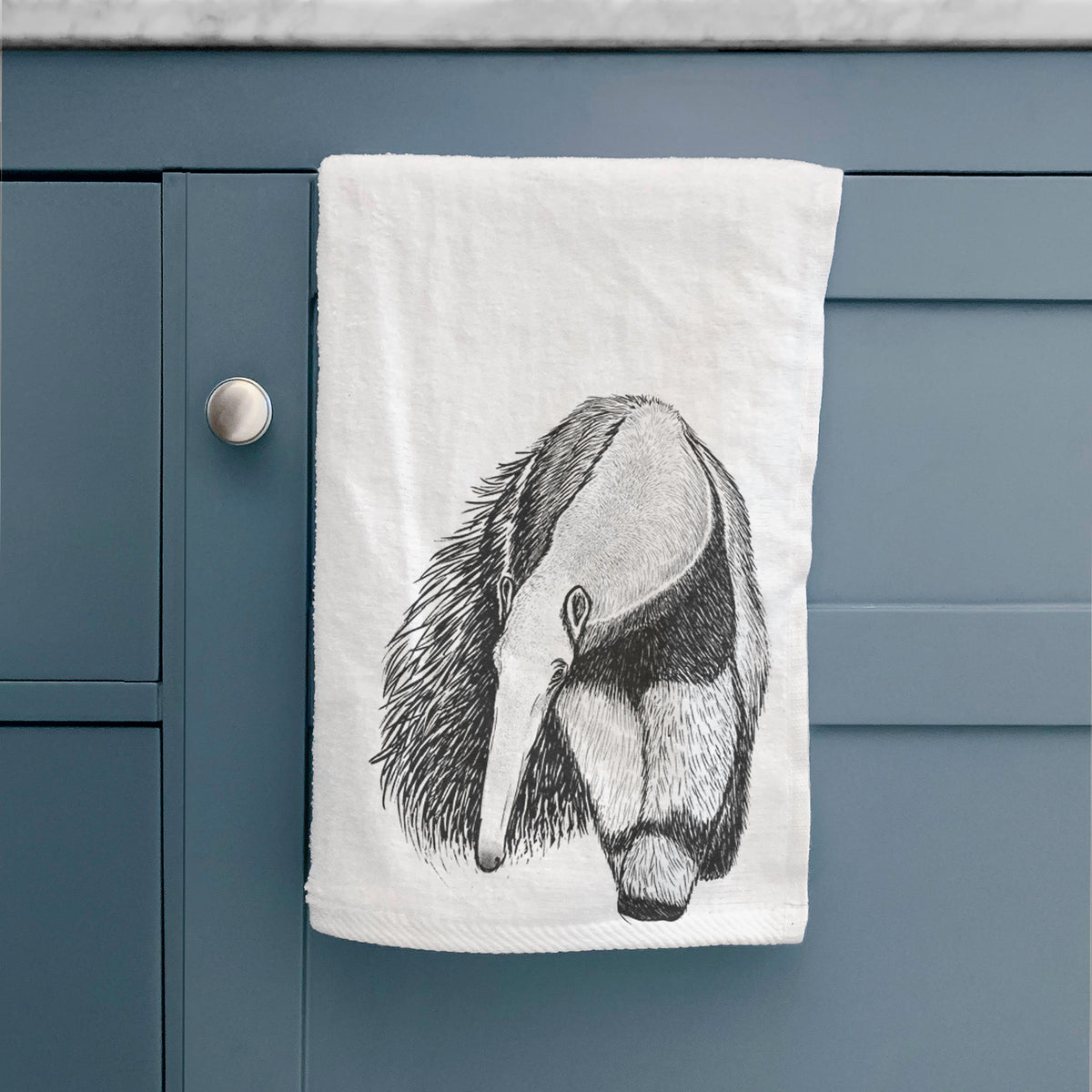 White hand towel printed with a detailed black ink illustration of a giant anteater with its long snout and bushy tail, hanging on a cabinet door.