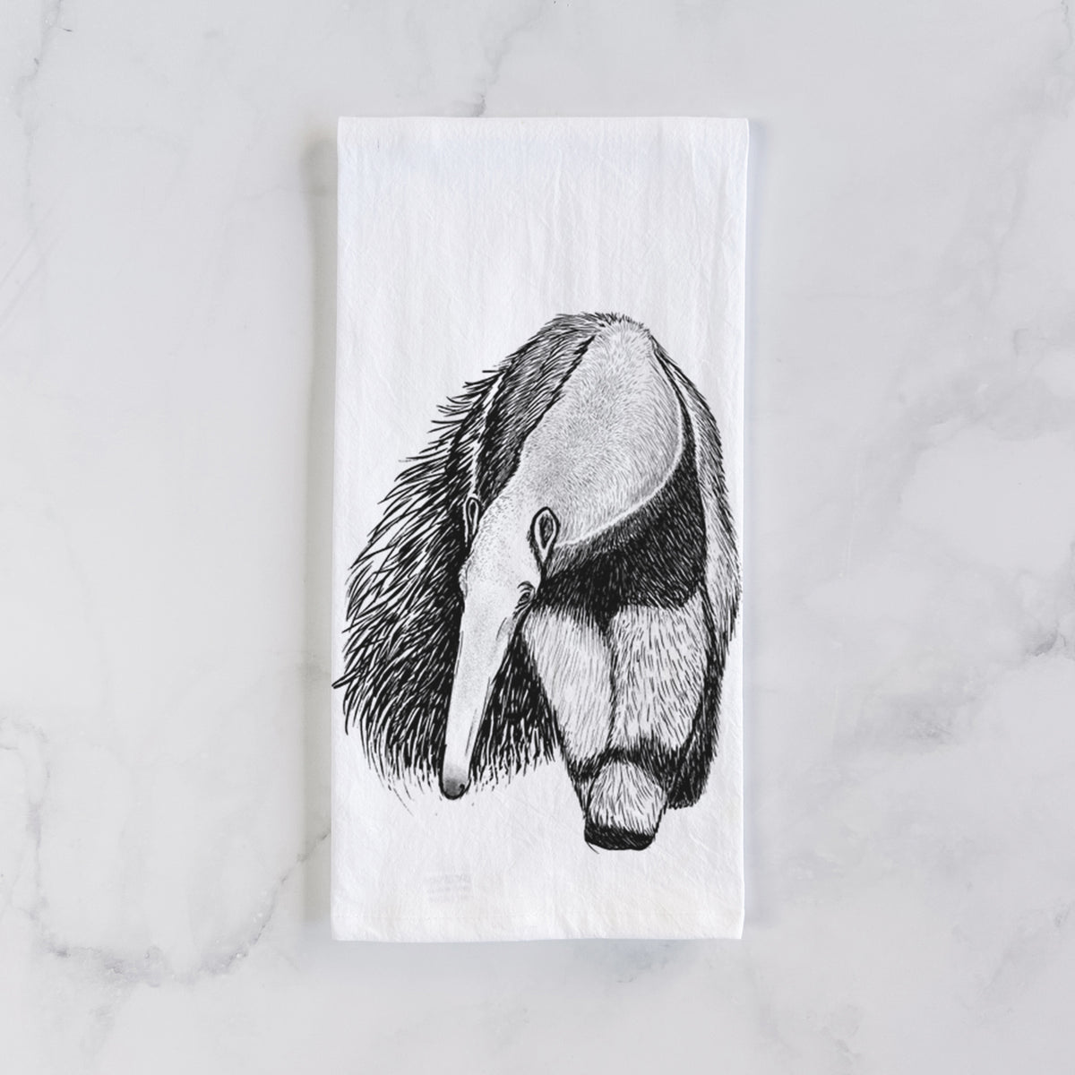 White cotton tea towel laid flat on marble, printed with a detailed black ink illustration of a giant anteater with its long snout and bushy tail.