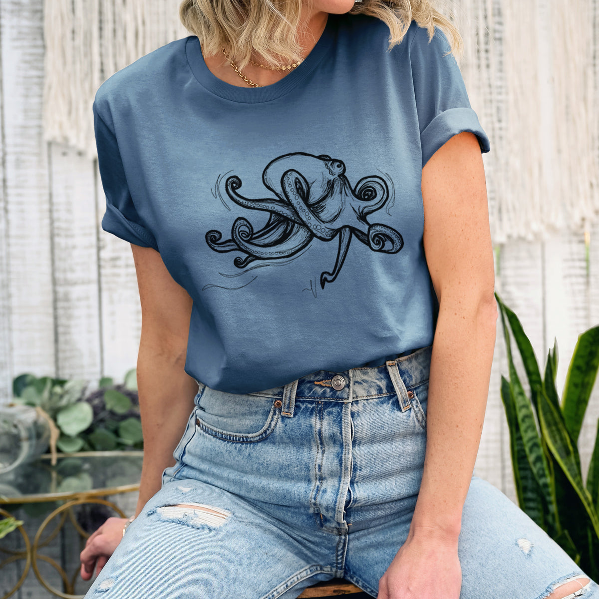 Woman wearing a steel blue lightweight cotton t-shirt printed with a black ink illustration of a giant Pacific octopus with curling tentacles.