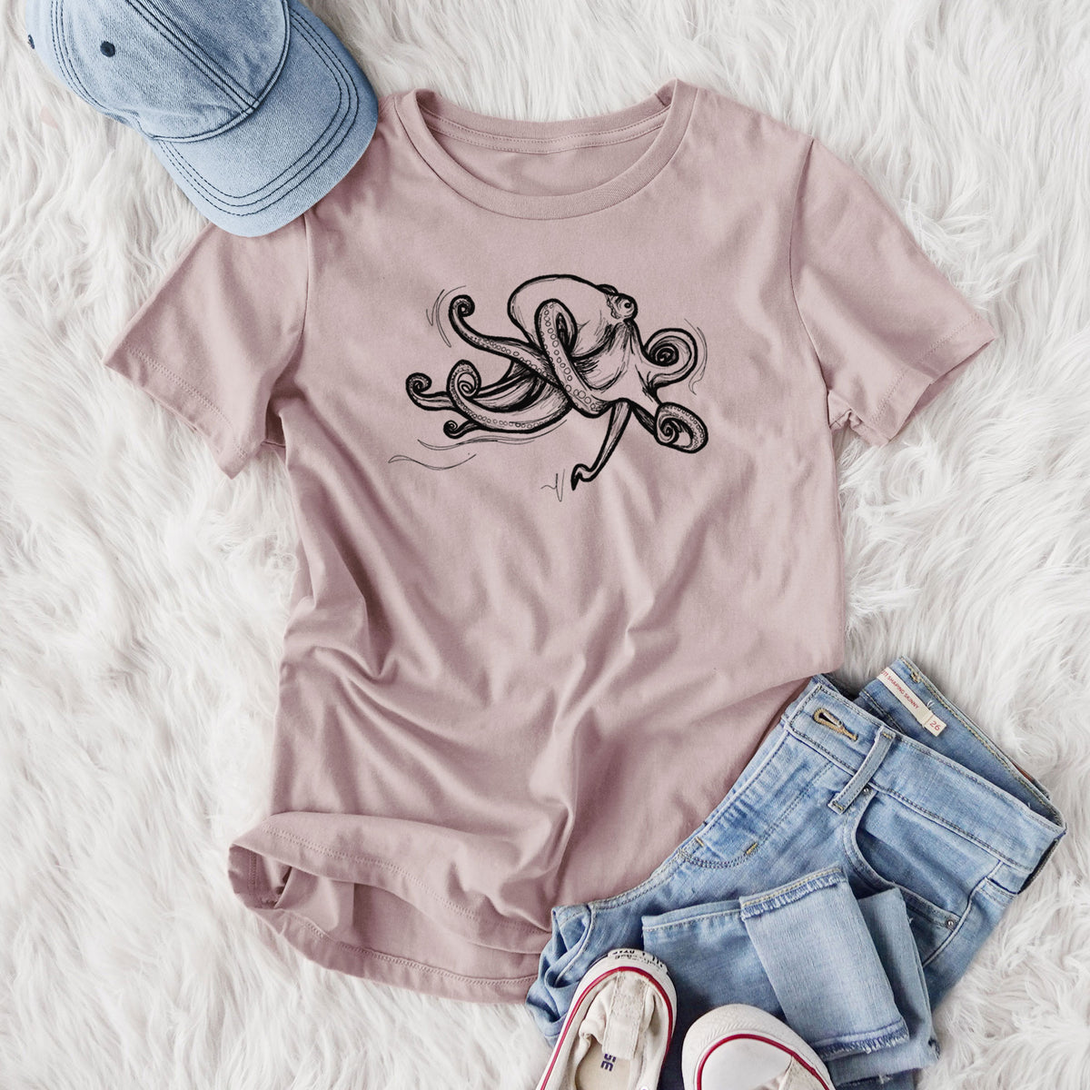 Women's relaxed fit cotton t-shirt printed with a black ink illustration of a giant Pacific octopus with curling tentacles, styled flat on a white faux fur rug with jeans.