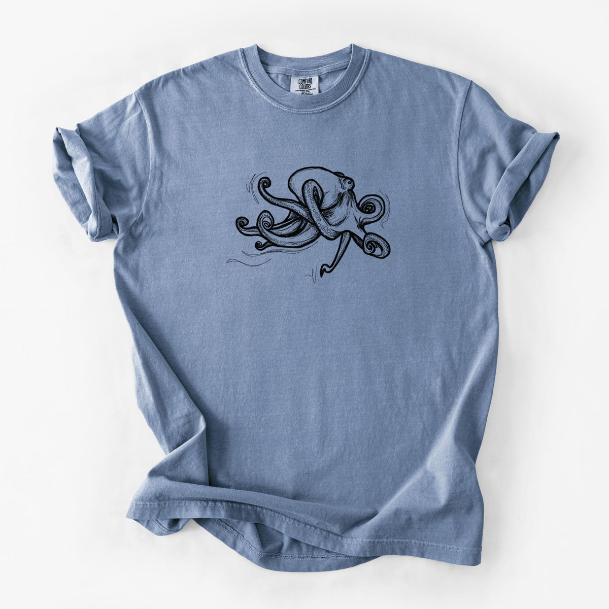 Blue jean Comfort Colors t-shirt laid flat, printed with a black ink illustration of a giant Pacific octopus with curling tentacles.