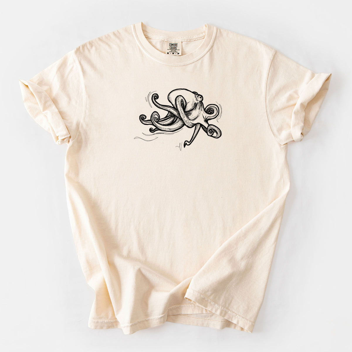 Ivory Comfort Colors t-shirt laid flat, printed with a black ink illustration of a giant Pacific octopus with curling tentacles.