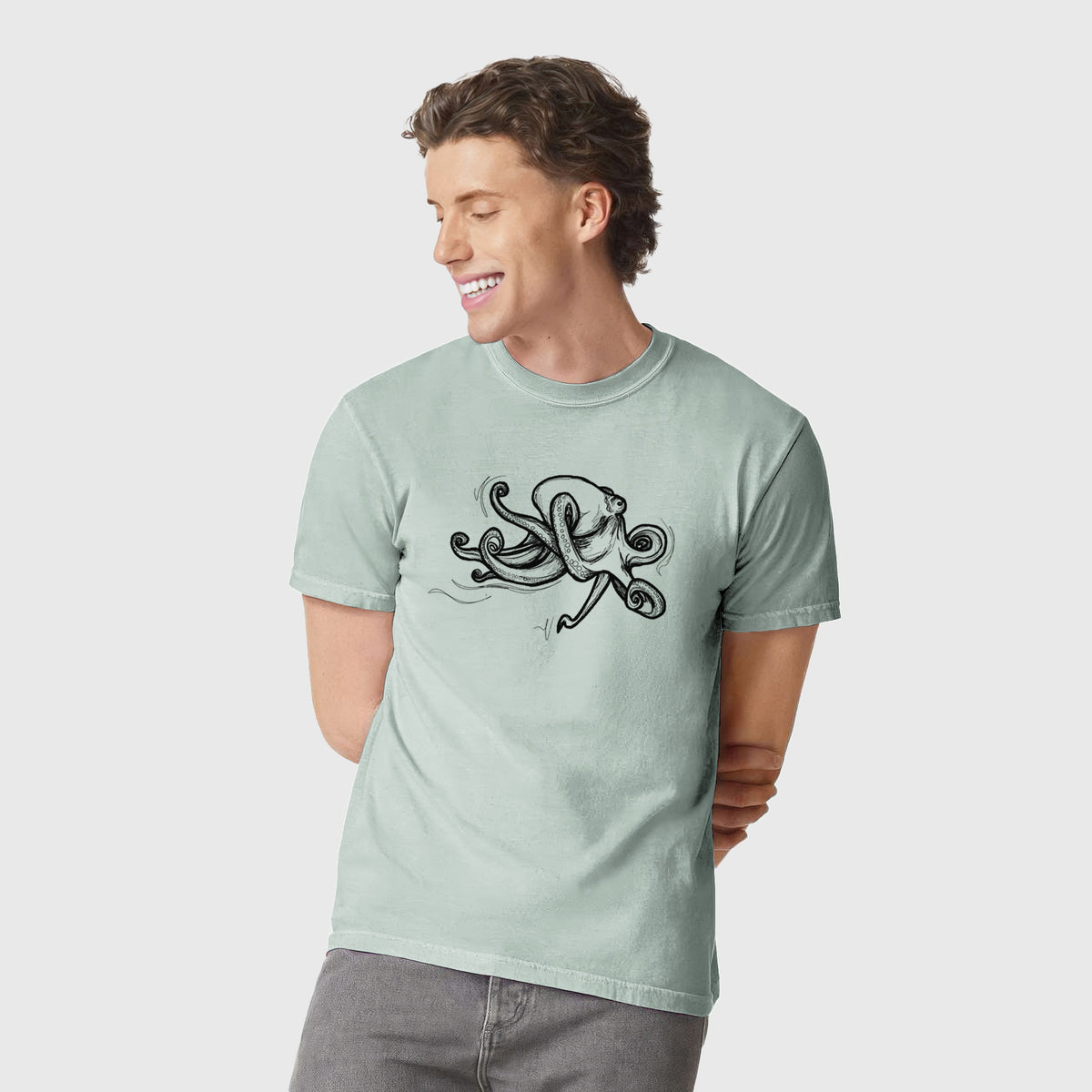 Man wearing a Comfort Colors t-shirt printed with a black ink illustration of a giant Pacific octopus with curling tentacles.