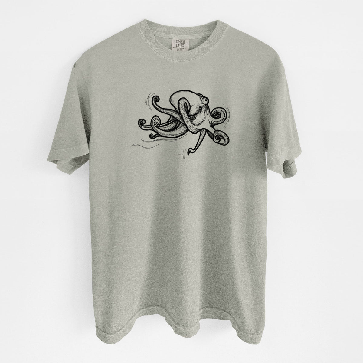 Sandstone beige Comfort Colors t-shirt laid flat, printed with a black ink illustration of a giant Pacific octopus with curling tentacles.